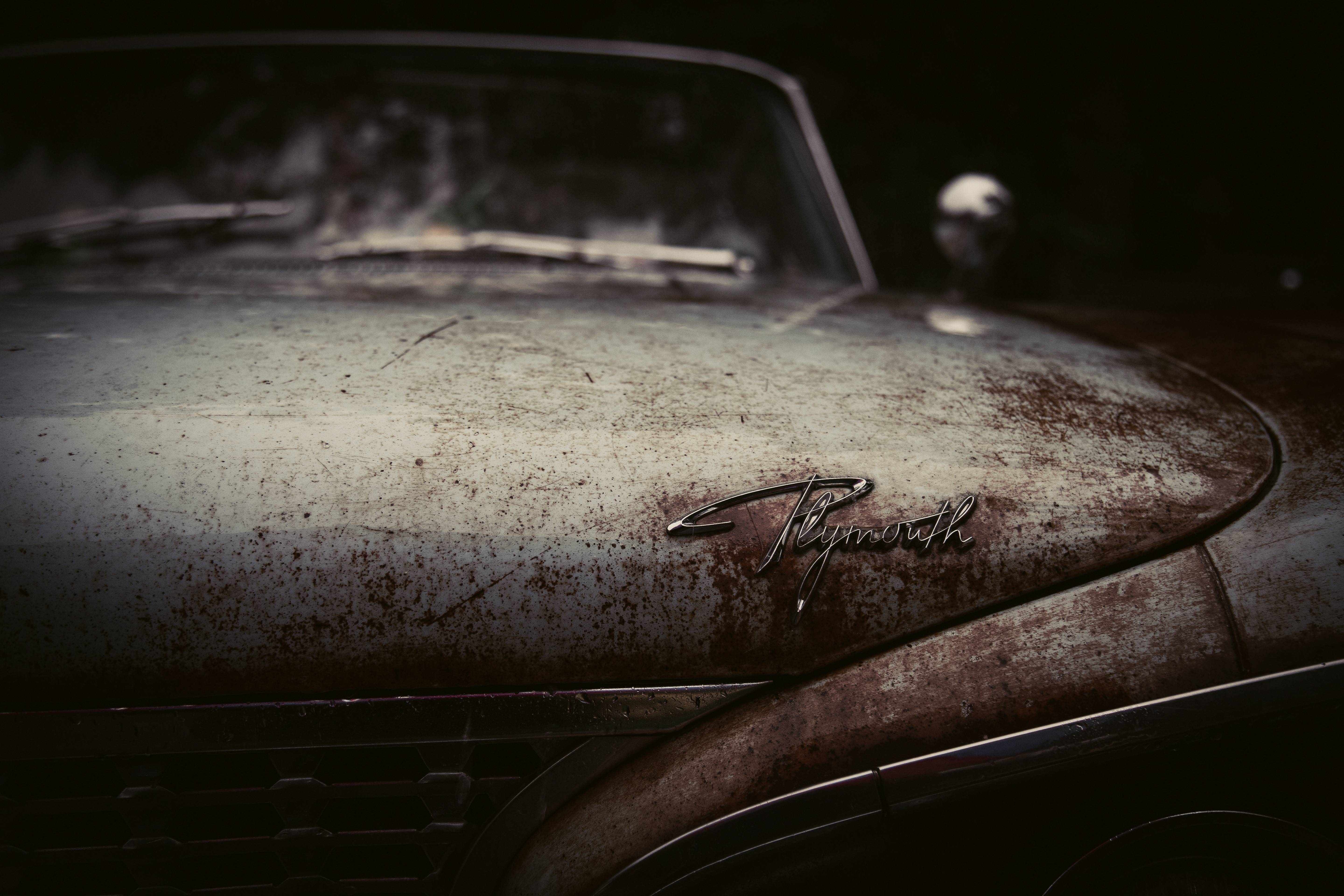 Close-up of a rusty Plymouth car hood emblem HD Wallpaper