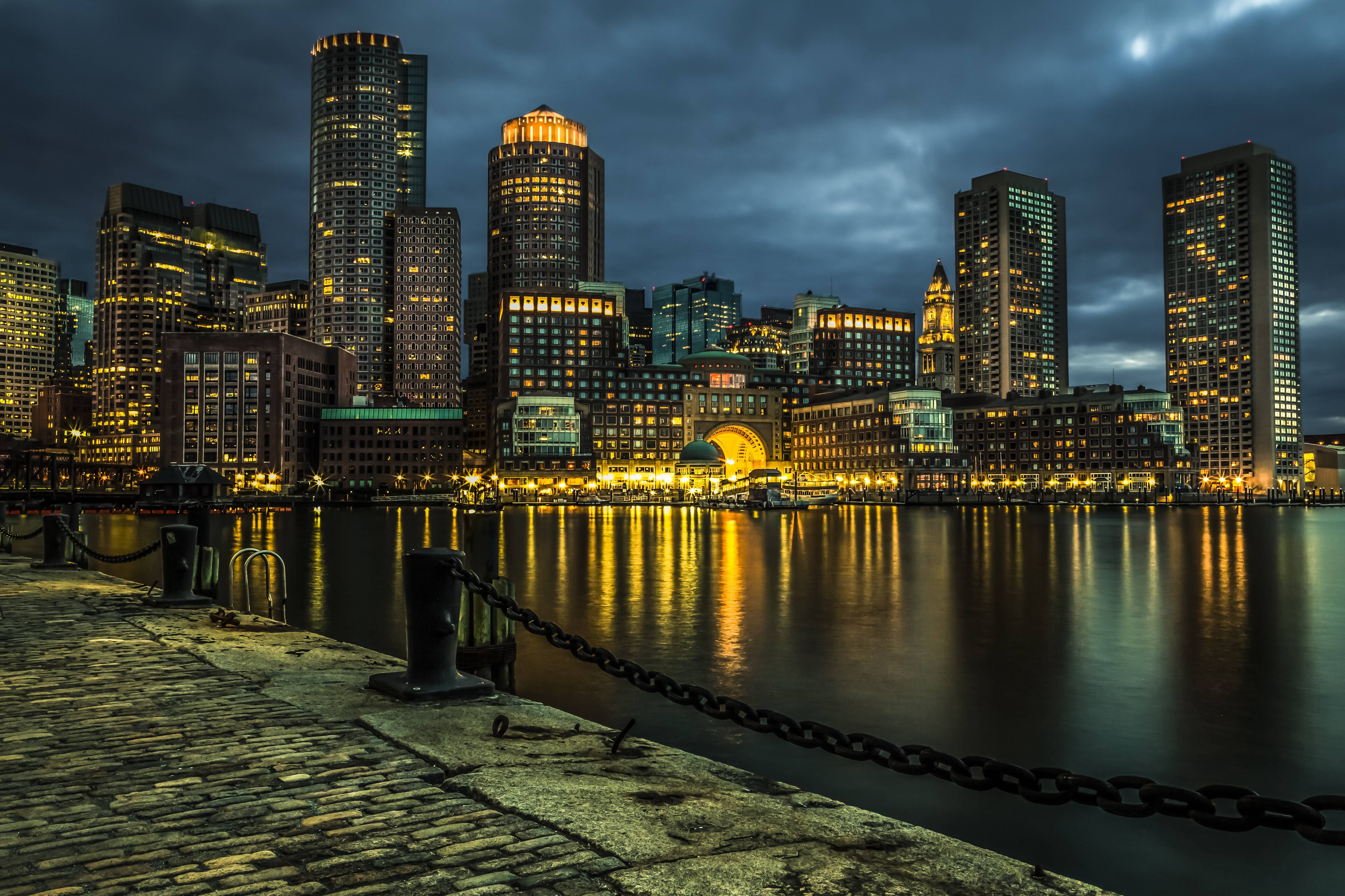 Boston cityscape at night with illuminated skyscrapers reflecting on water HD Wallpaper