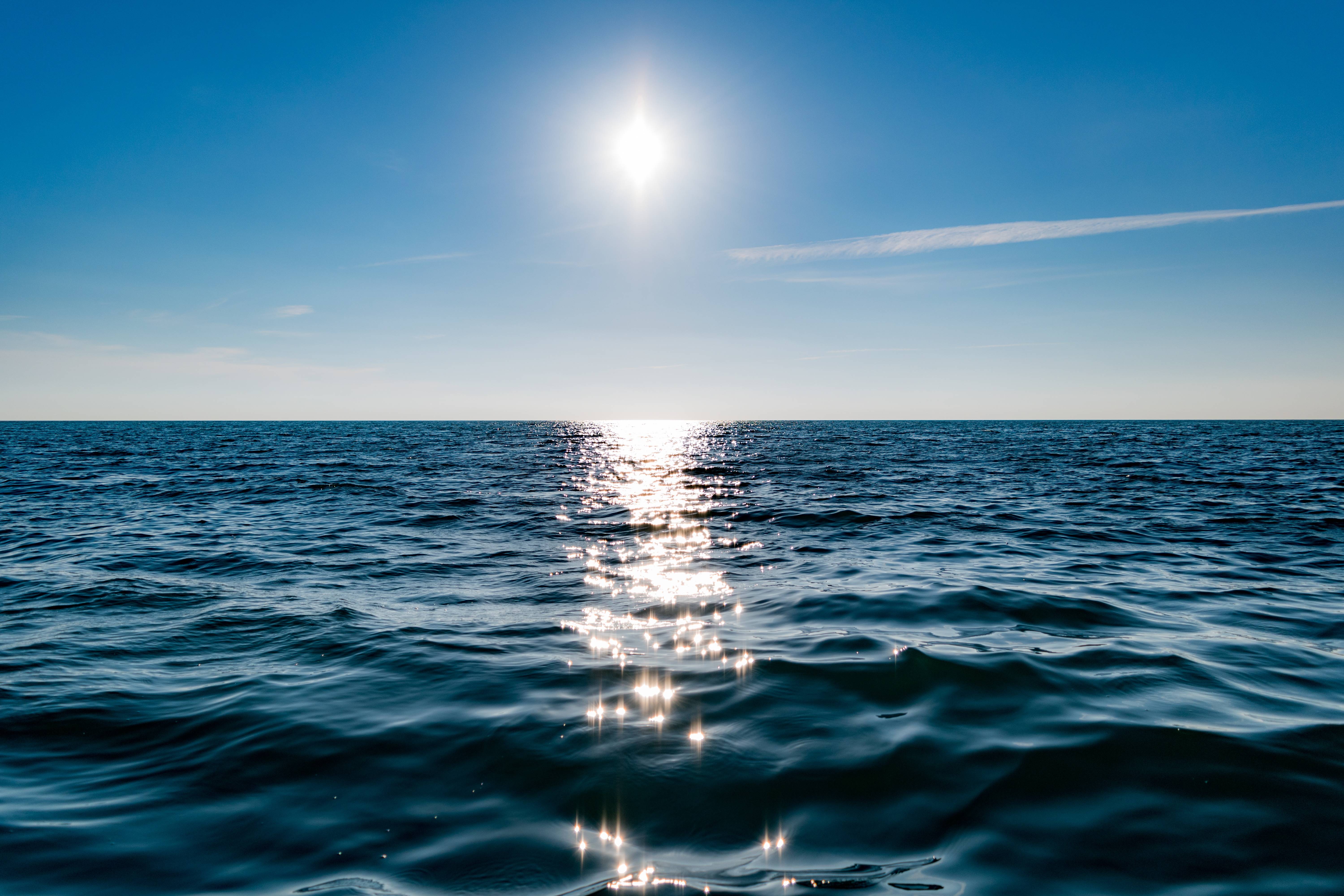 Sun reflecting on the ocean horizon under a clear blue sky HD Wallpaper