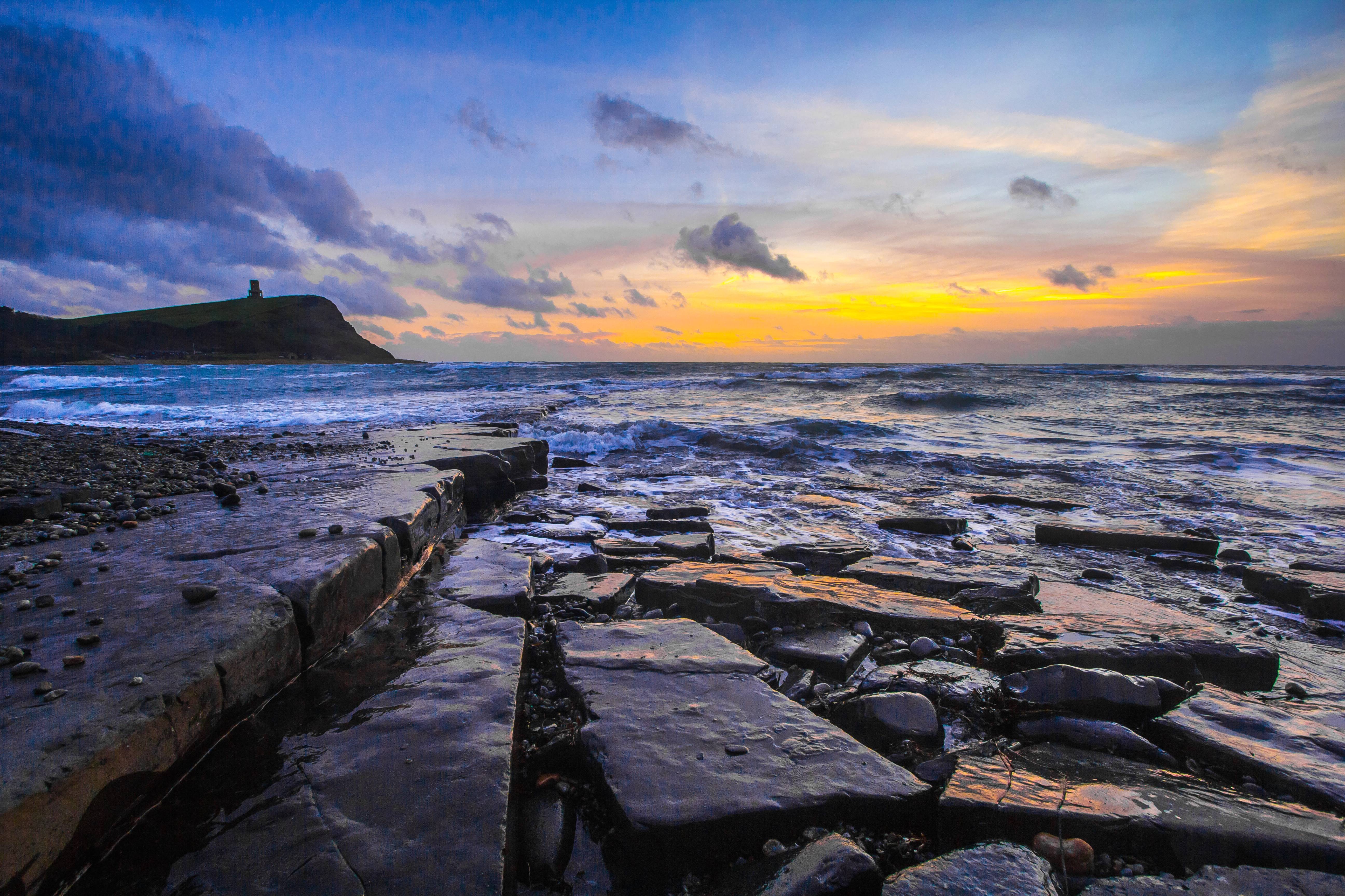 Sunset over the coast of Dorset with a tower on a hill HD Wallpaper