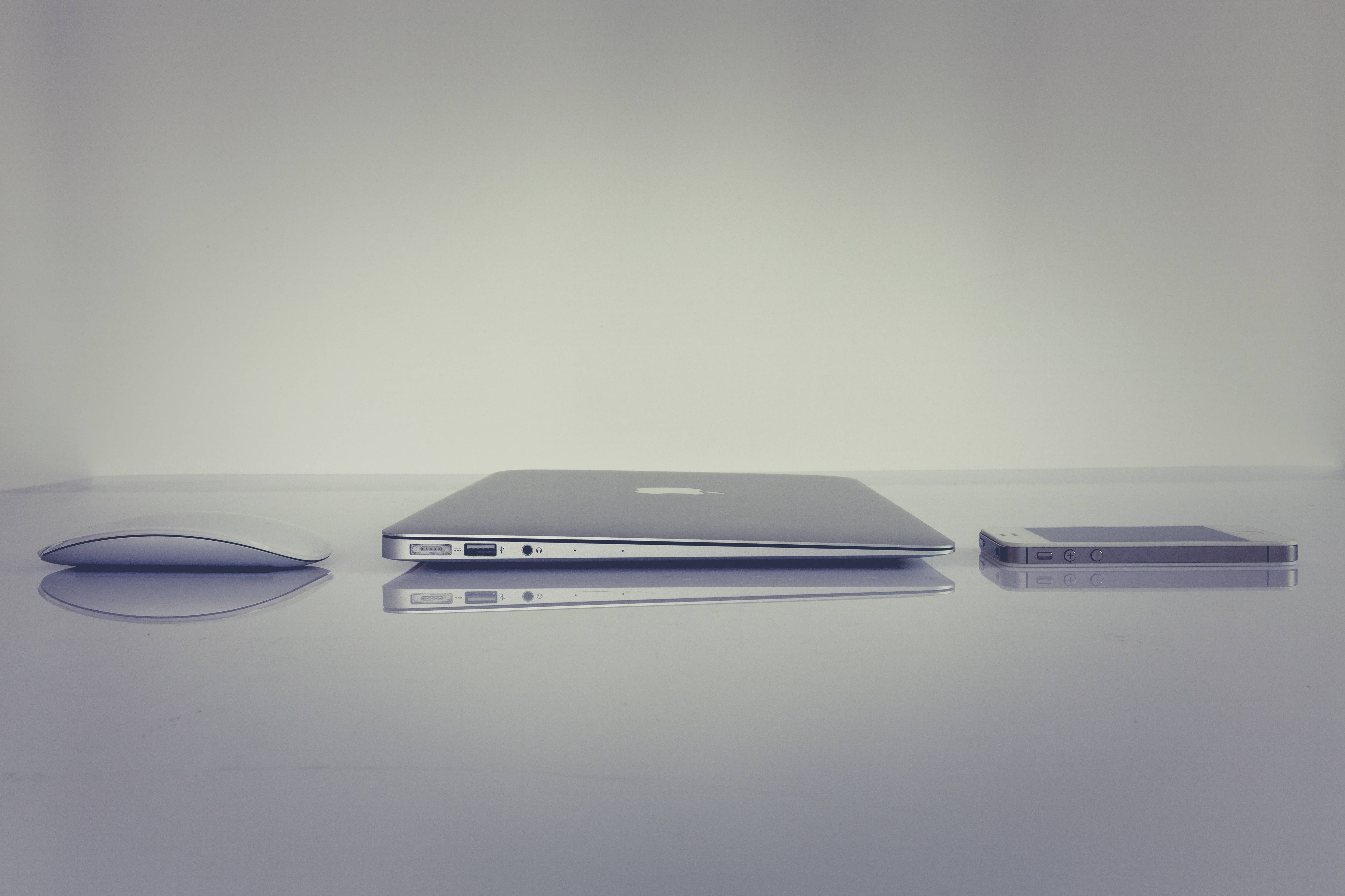 Apple MacBook, iPhone, and Mouse on a Reflective Surface HD Wallpaper