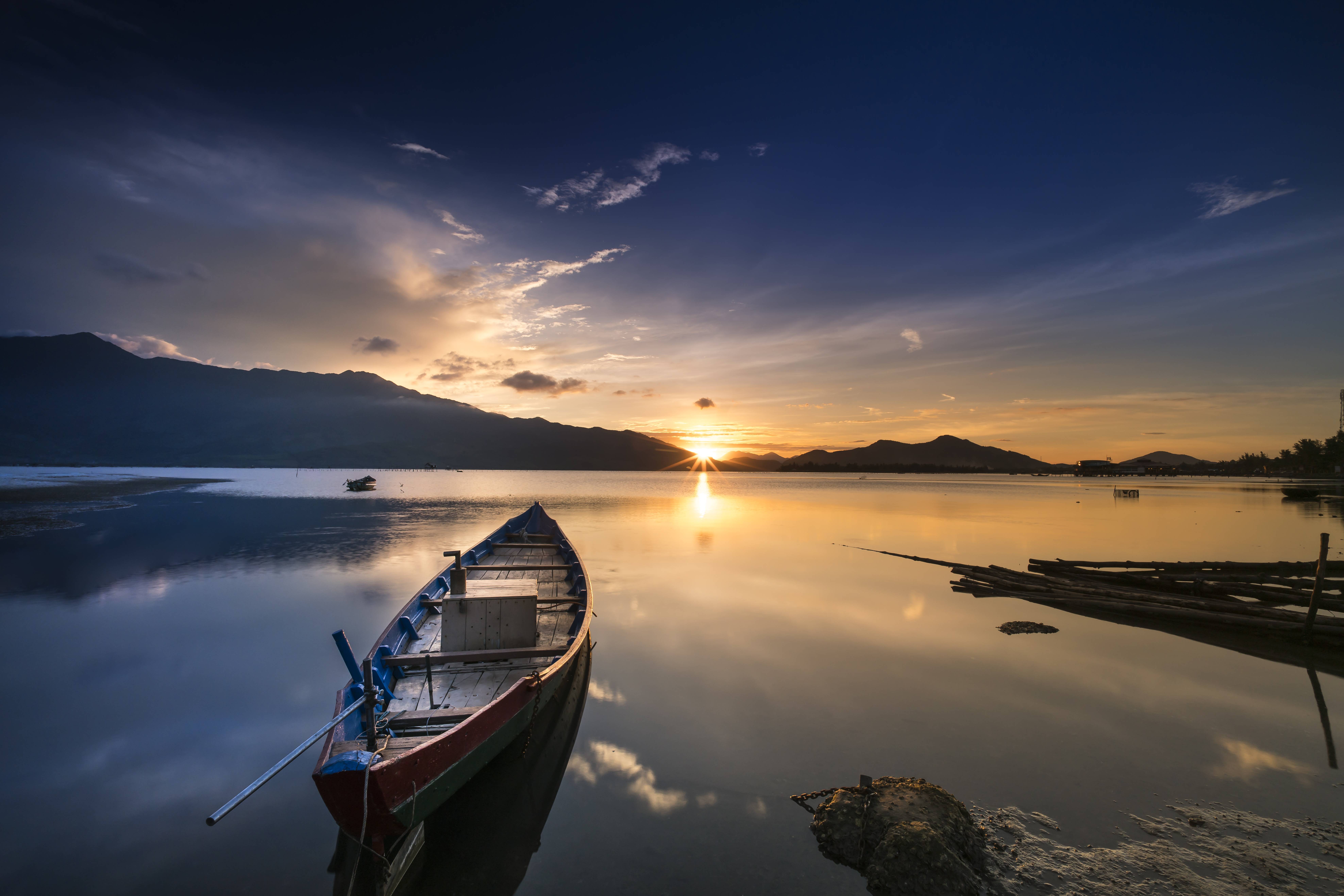 Boat on calm water at sunset with mountains HD Wallpaper