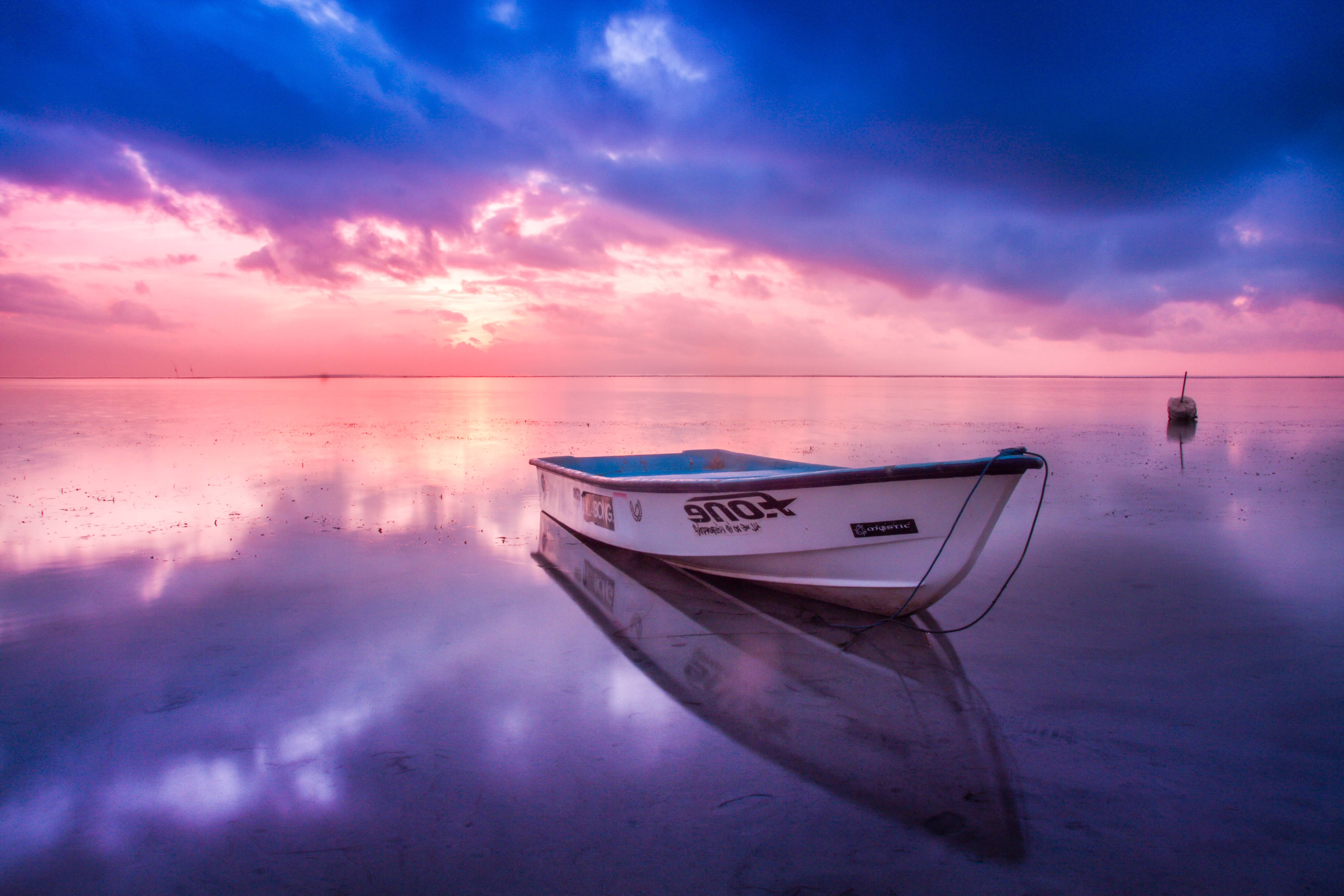 Boat on calm water at sunset with colorful clouds HD Wallpaper