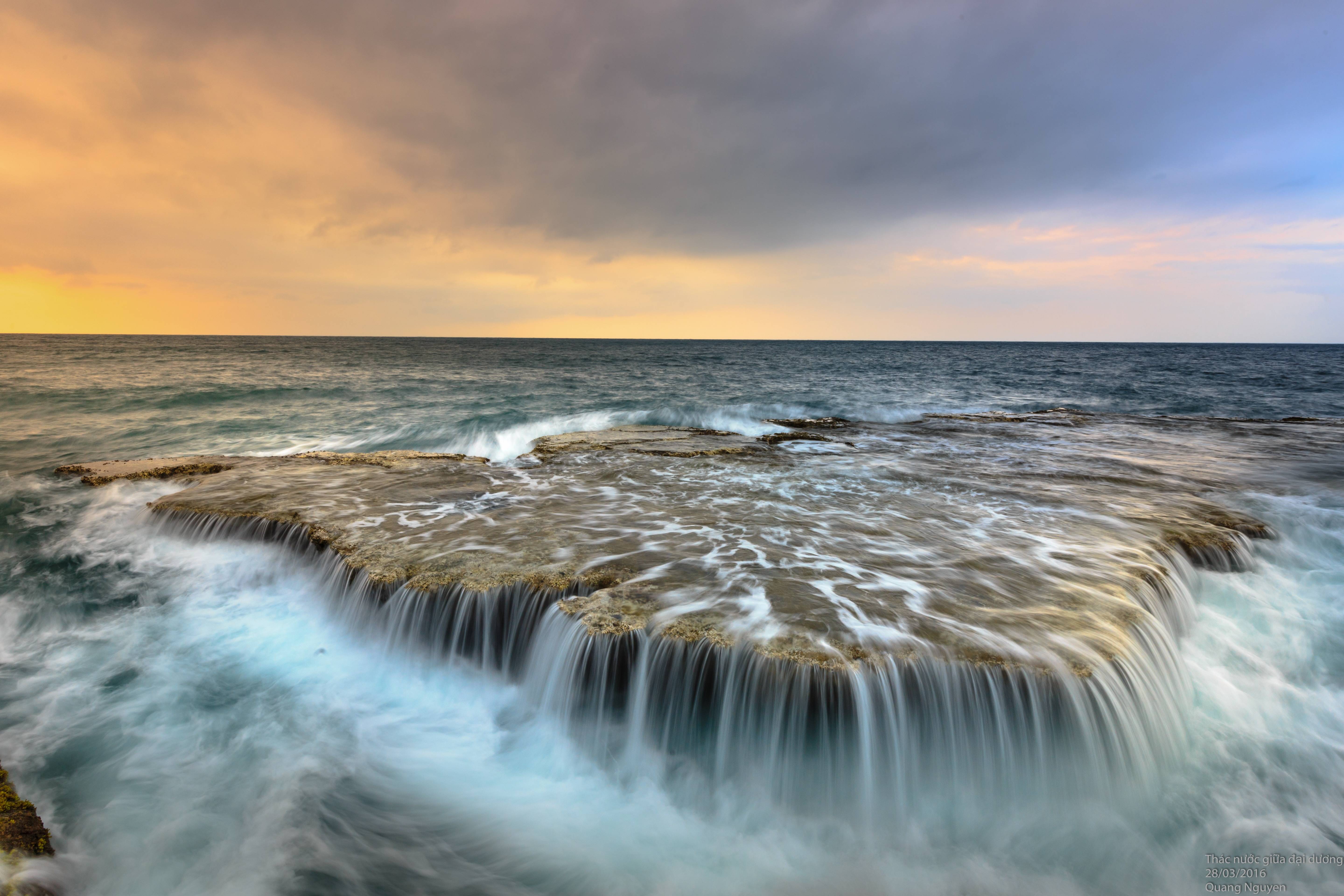 Ocean waves crashing over rocks at sunset HD Wallpaper
