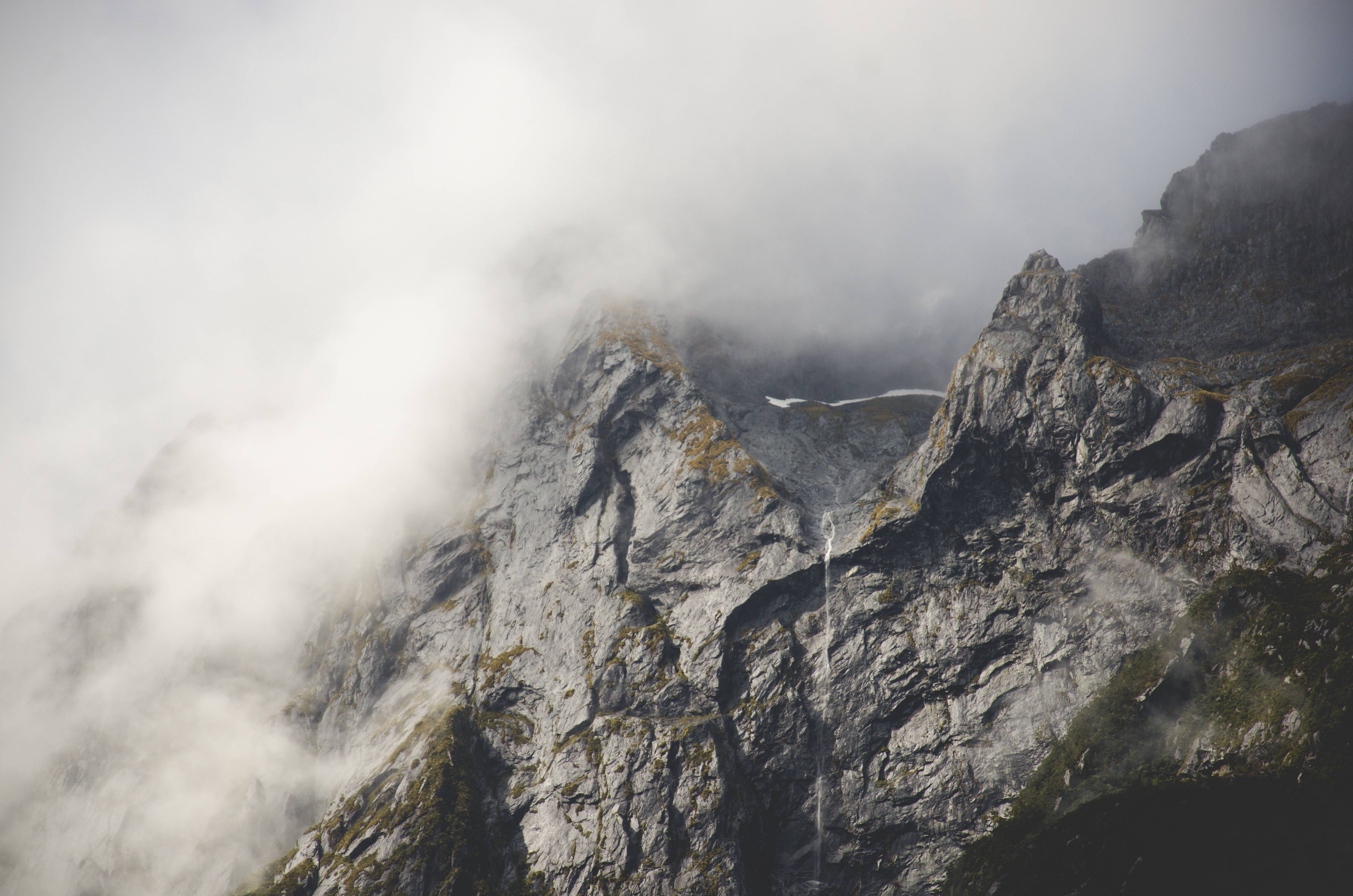 Misty mountains with rocky slopes and a waterfall HD Wallpaper