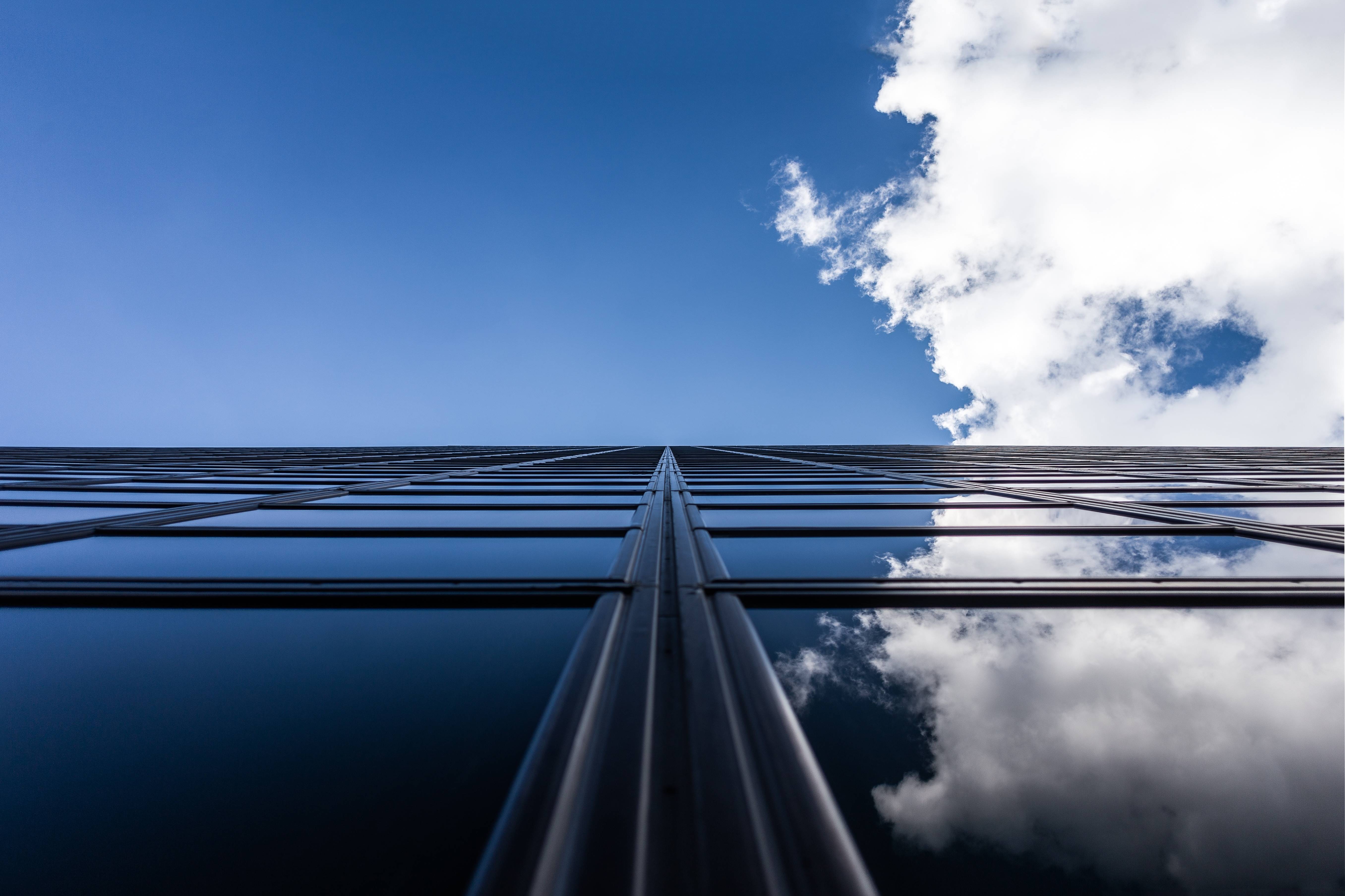 Low angle view of a modern skyscraper facade reflecting the sky HD Wallpaper
