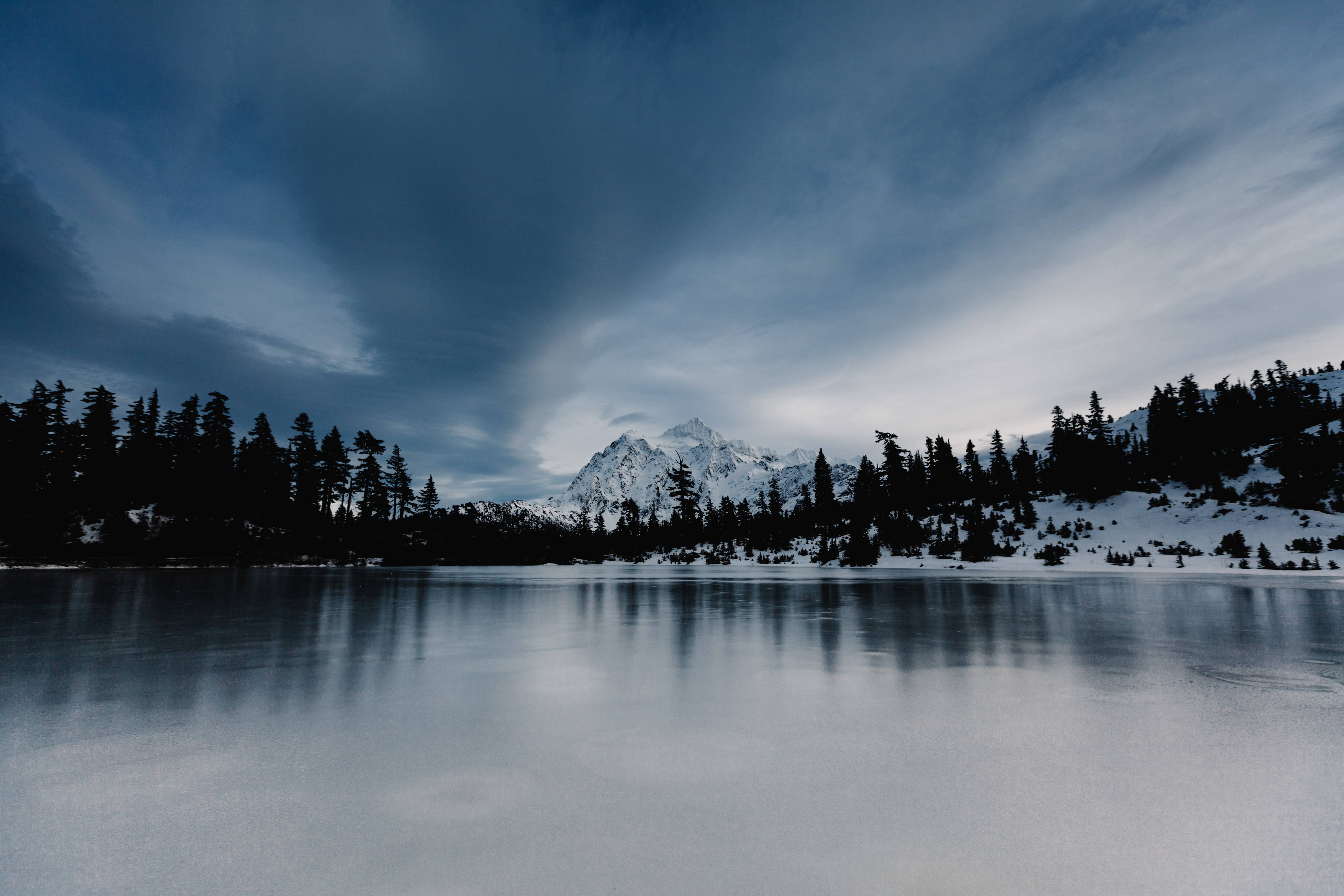 Snowy mountain range reflected in a frozen lake HD Wallpaper