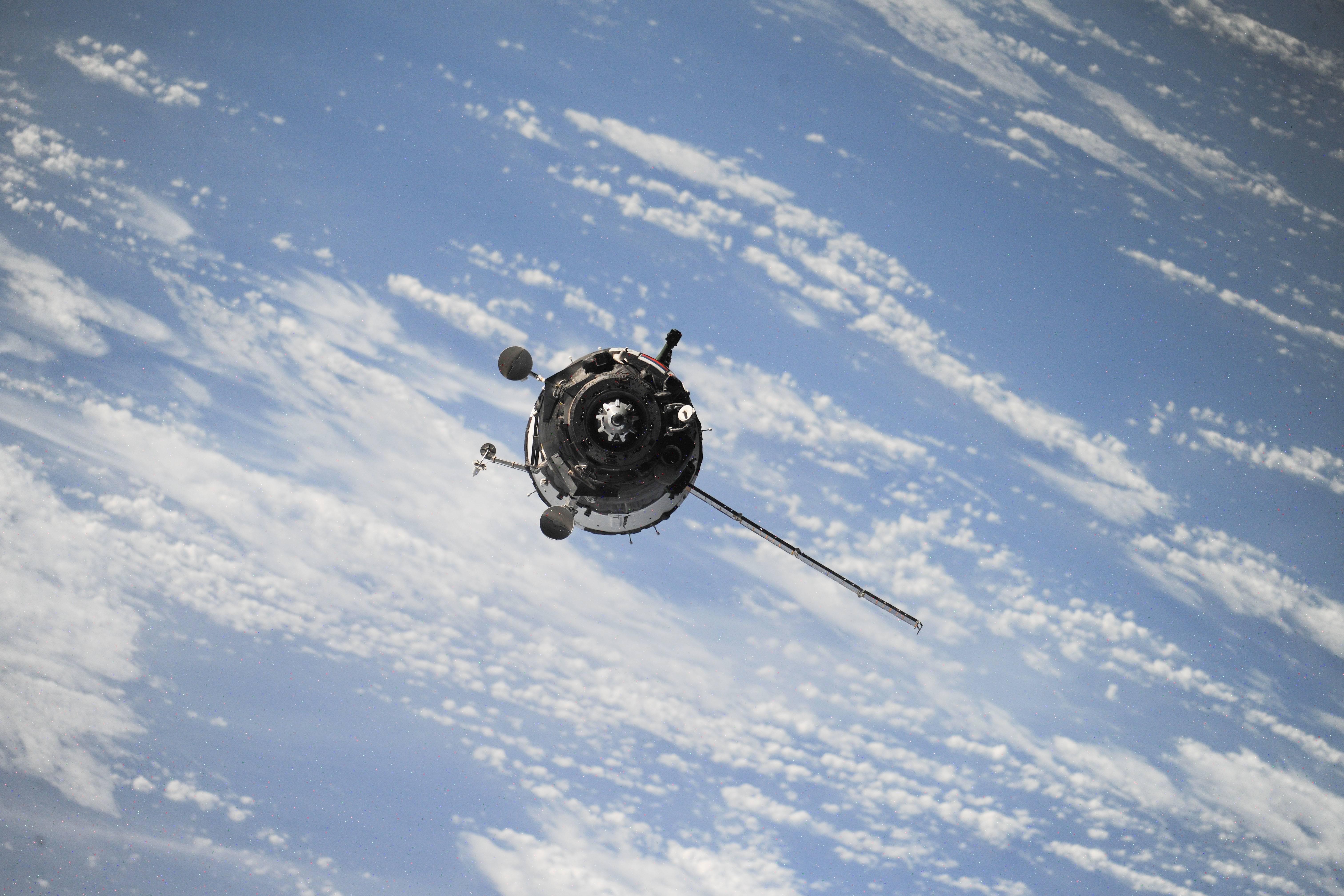 Space satellite orbiting Earth with clouds HD Wallpaper