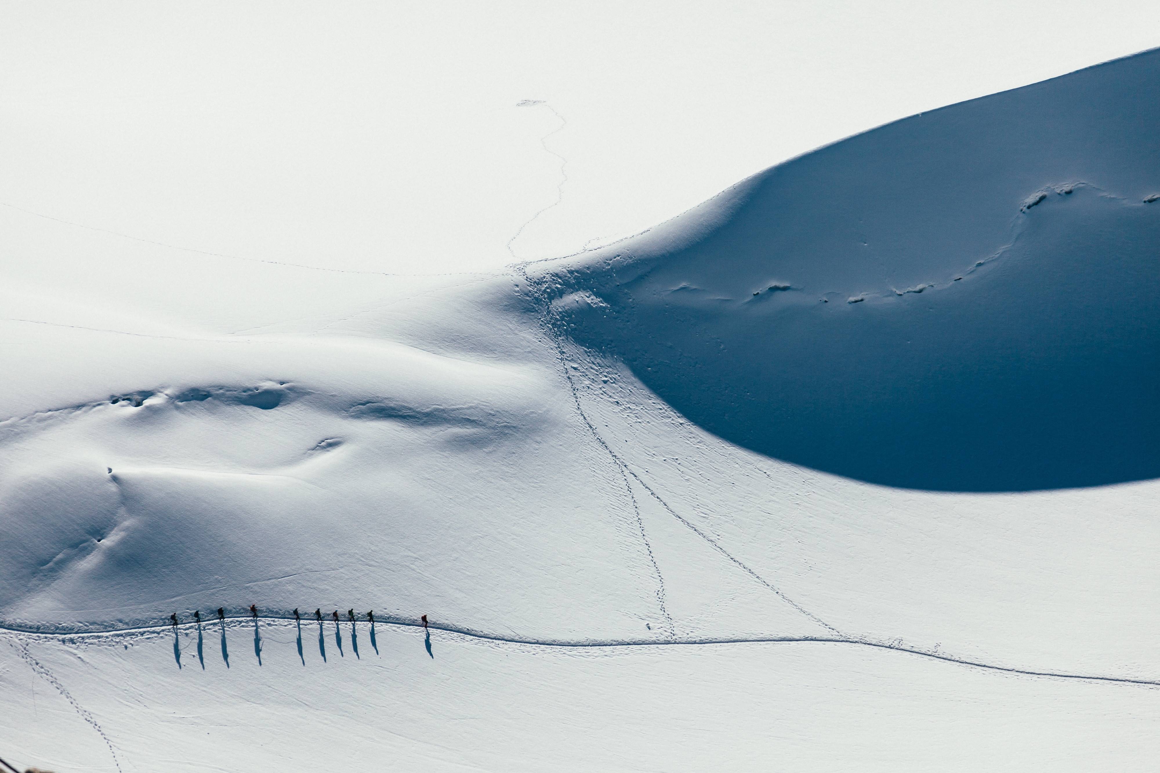 Group of hikers on a snowy mountain expedition HD Wallpaper