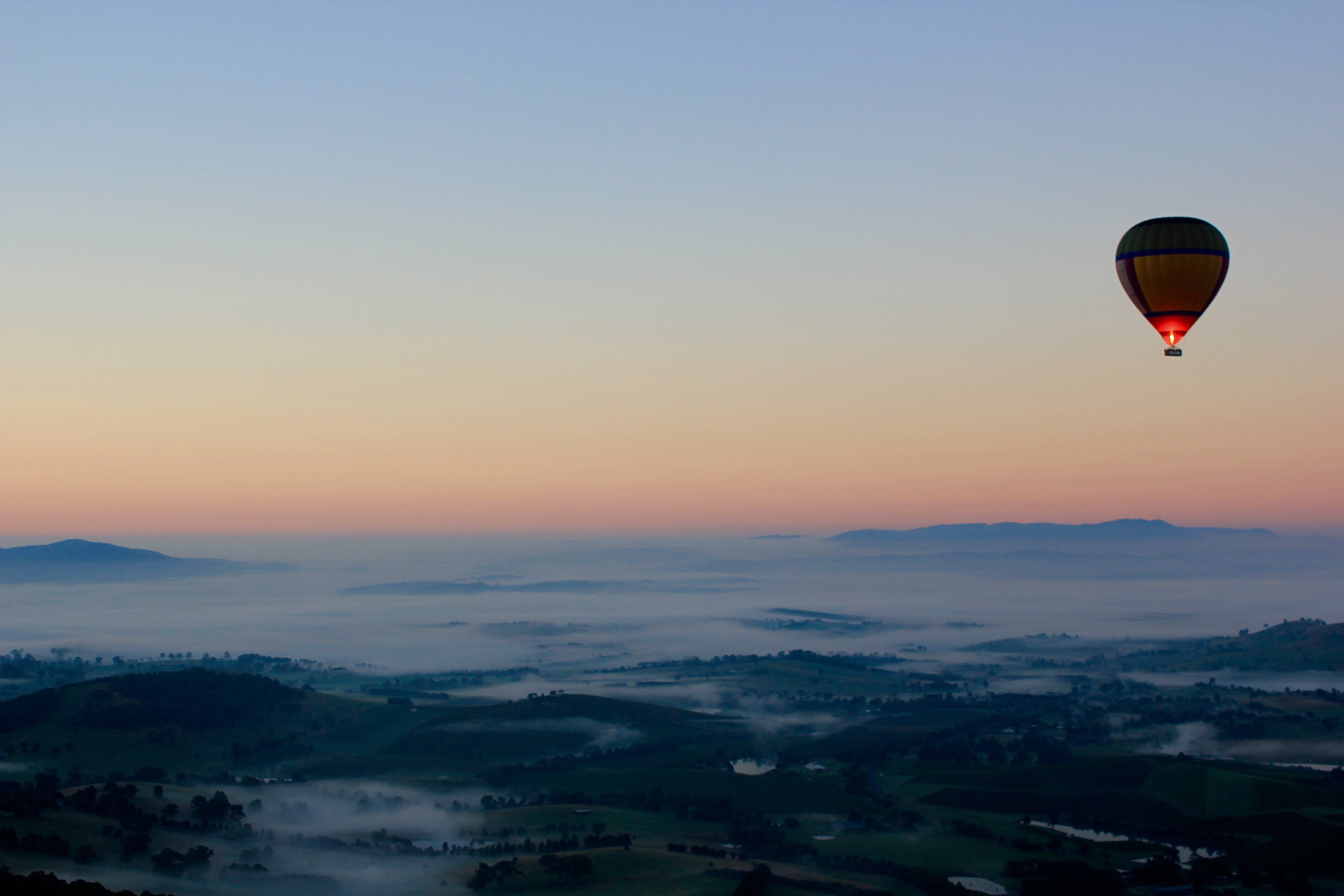 Hot air balloon over misty landscape at sunrise HD Wallpaper