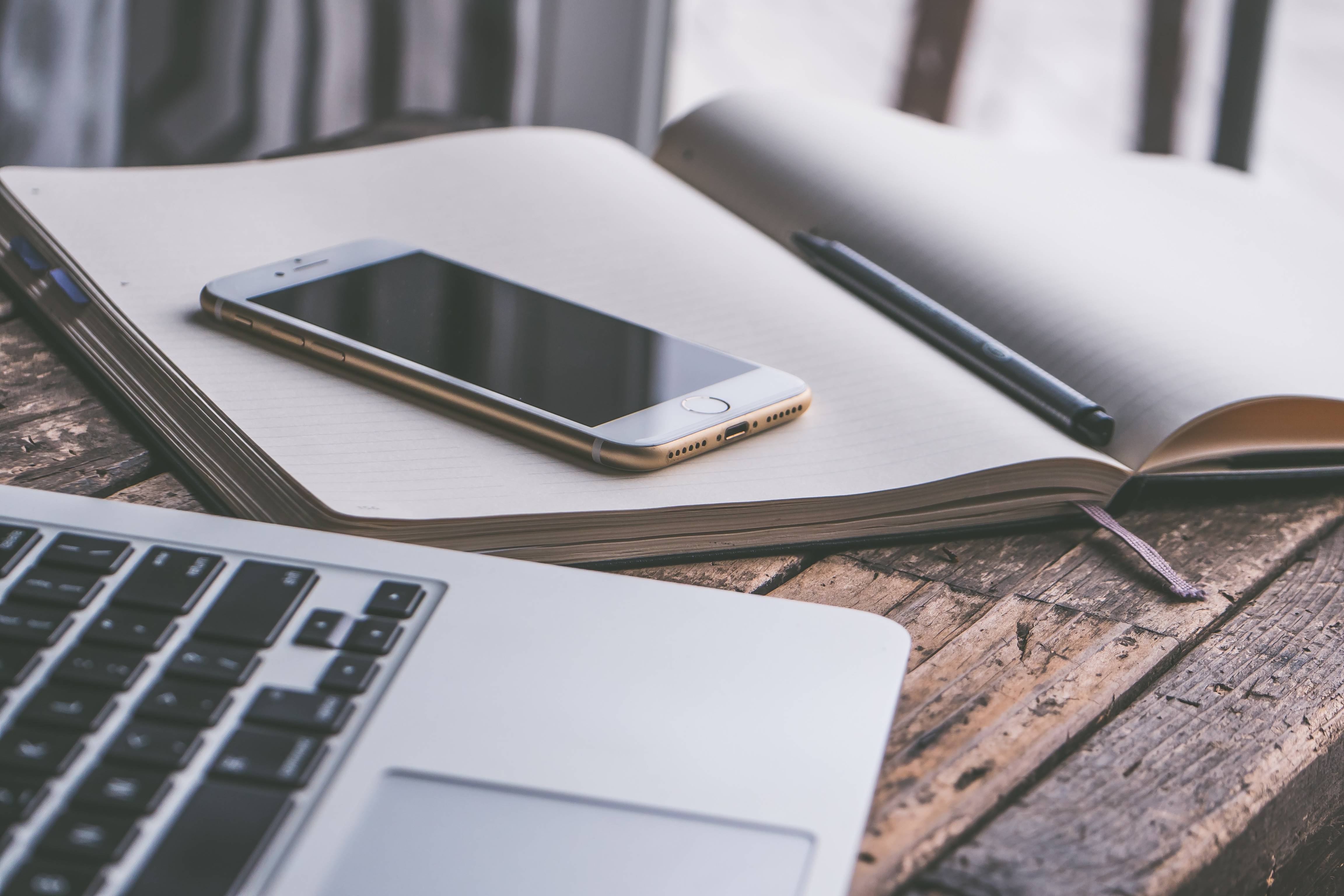 iPhone on a notebook next to a laptop HD Wallpaper