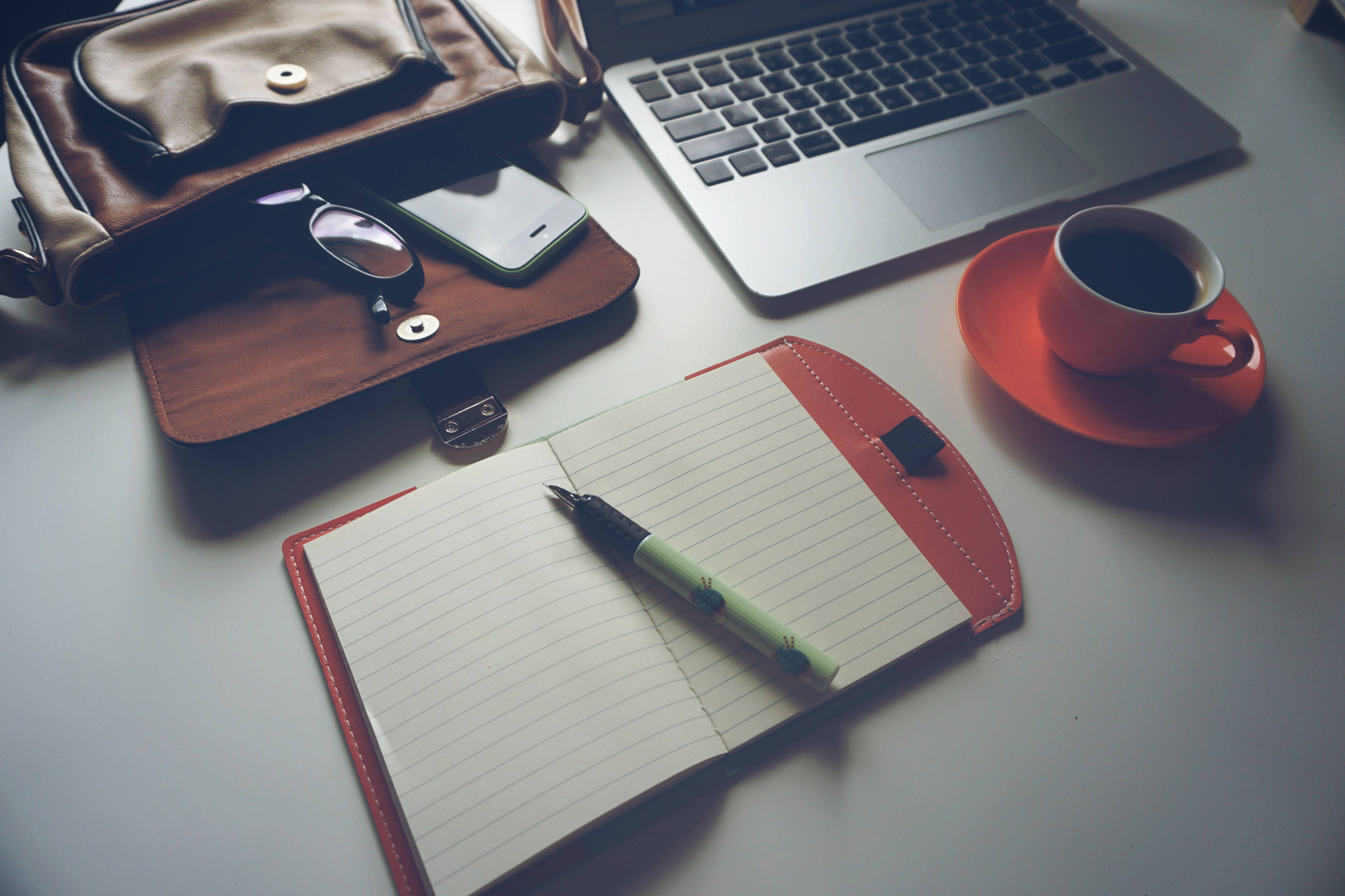 Laptop, notebook, coffee, and bag on a desk HD Wallpaper