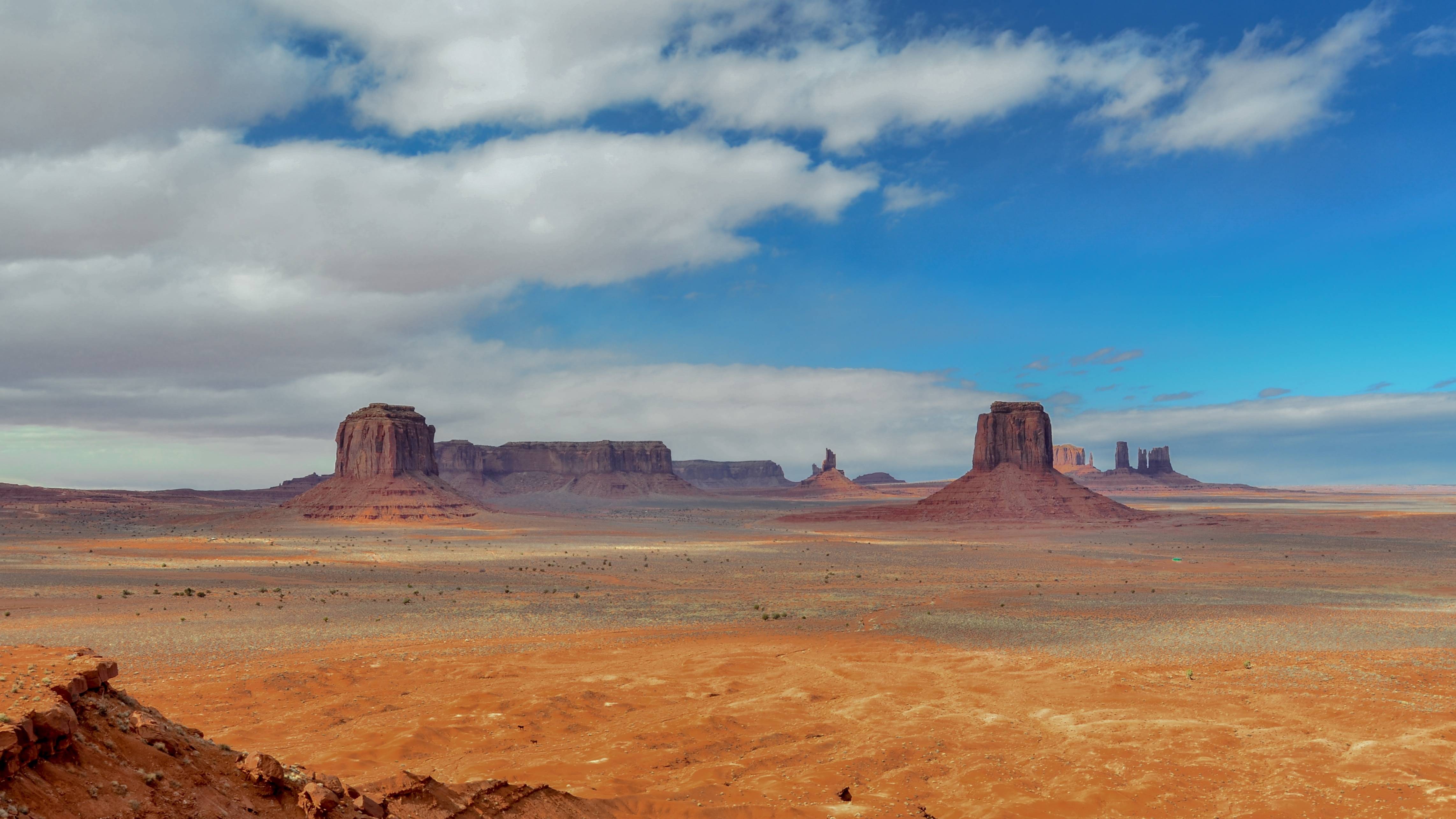 Monument Valley desert landscape with mesas under a blue sky HD Wallpaper
