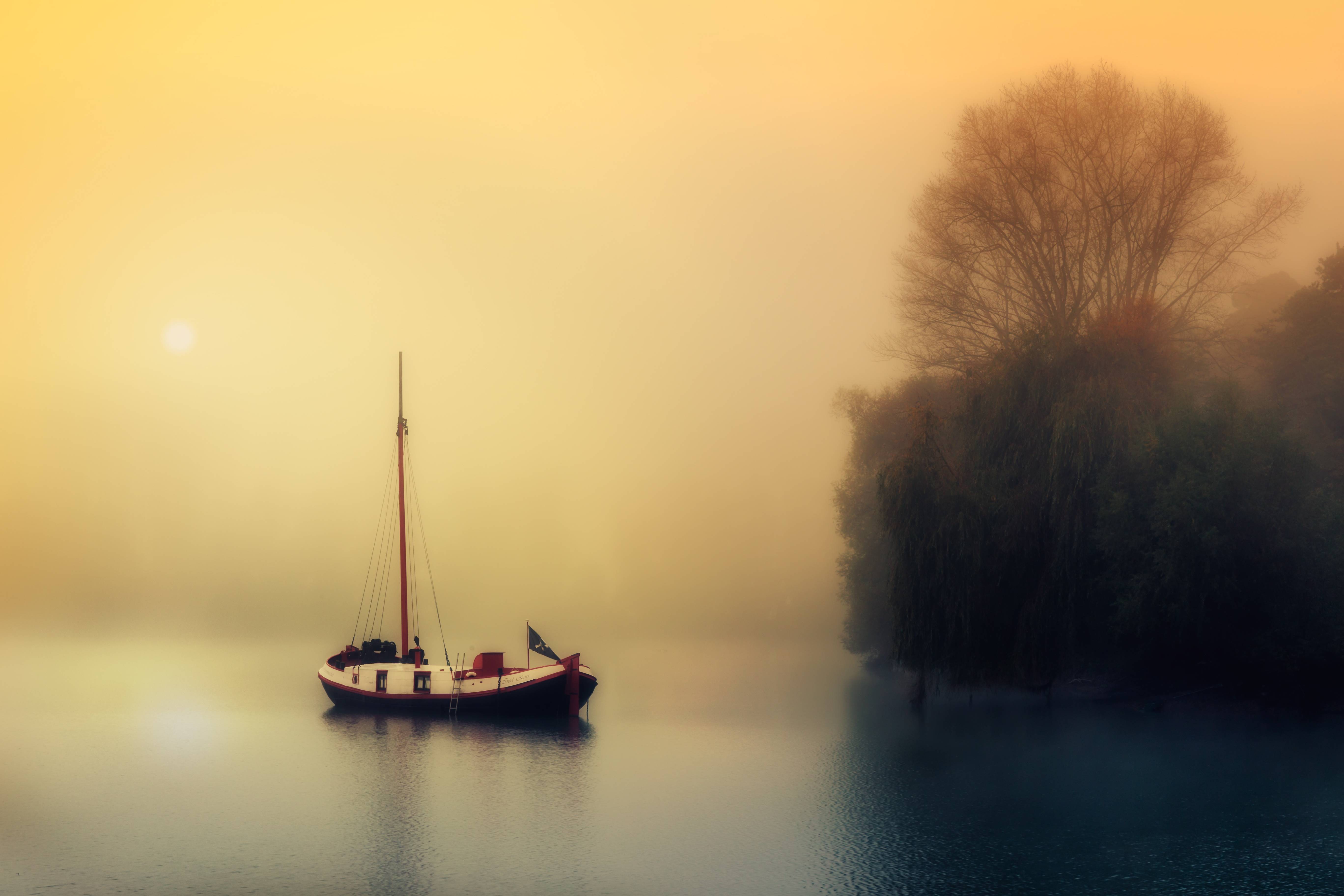 A lone sailboat on a foggy lake at sunrise HD Wallpaper
