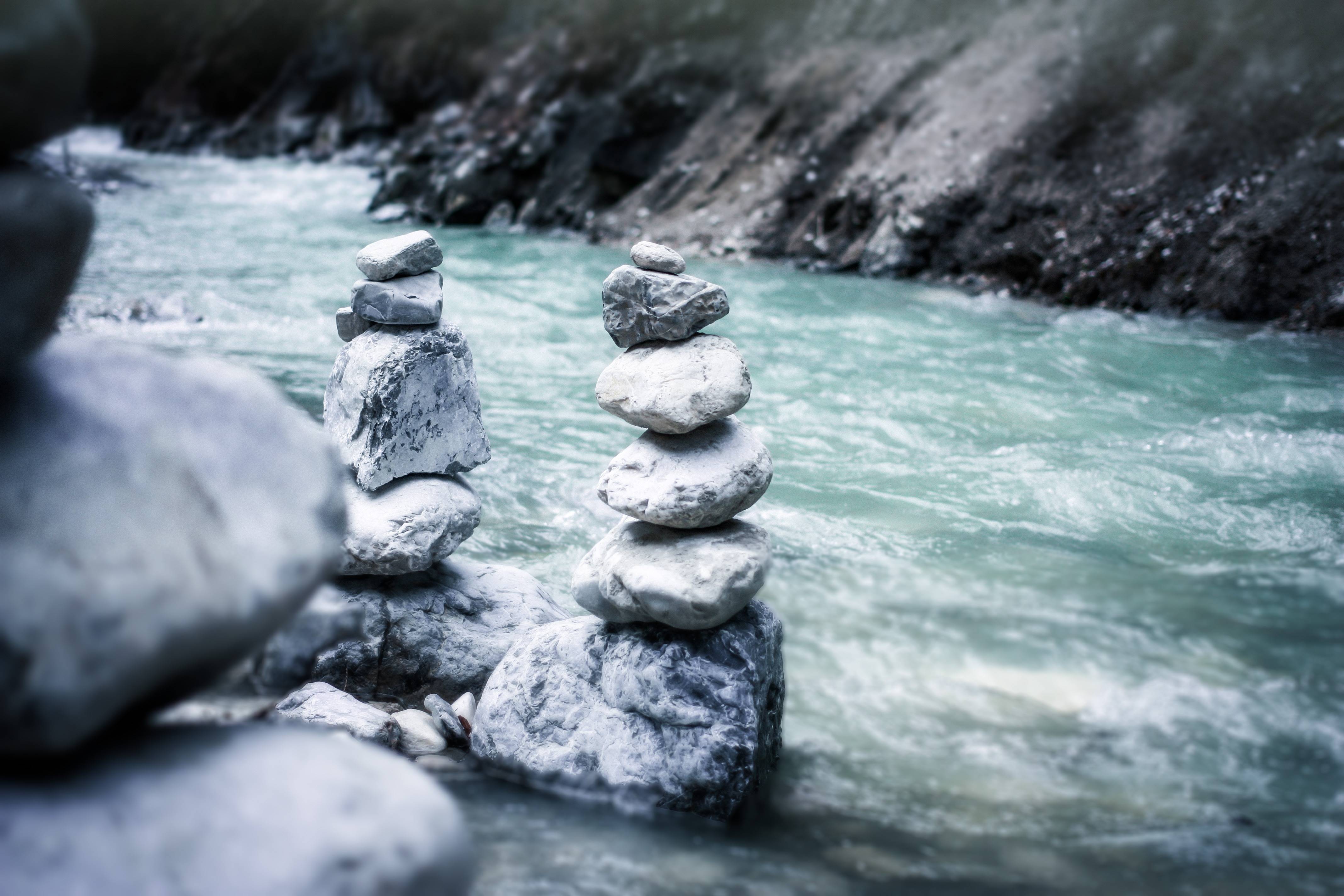 Stacked rocks in a flowing river HD Wallpaper