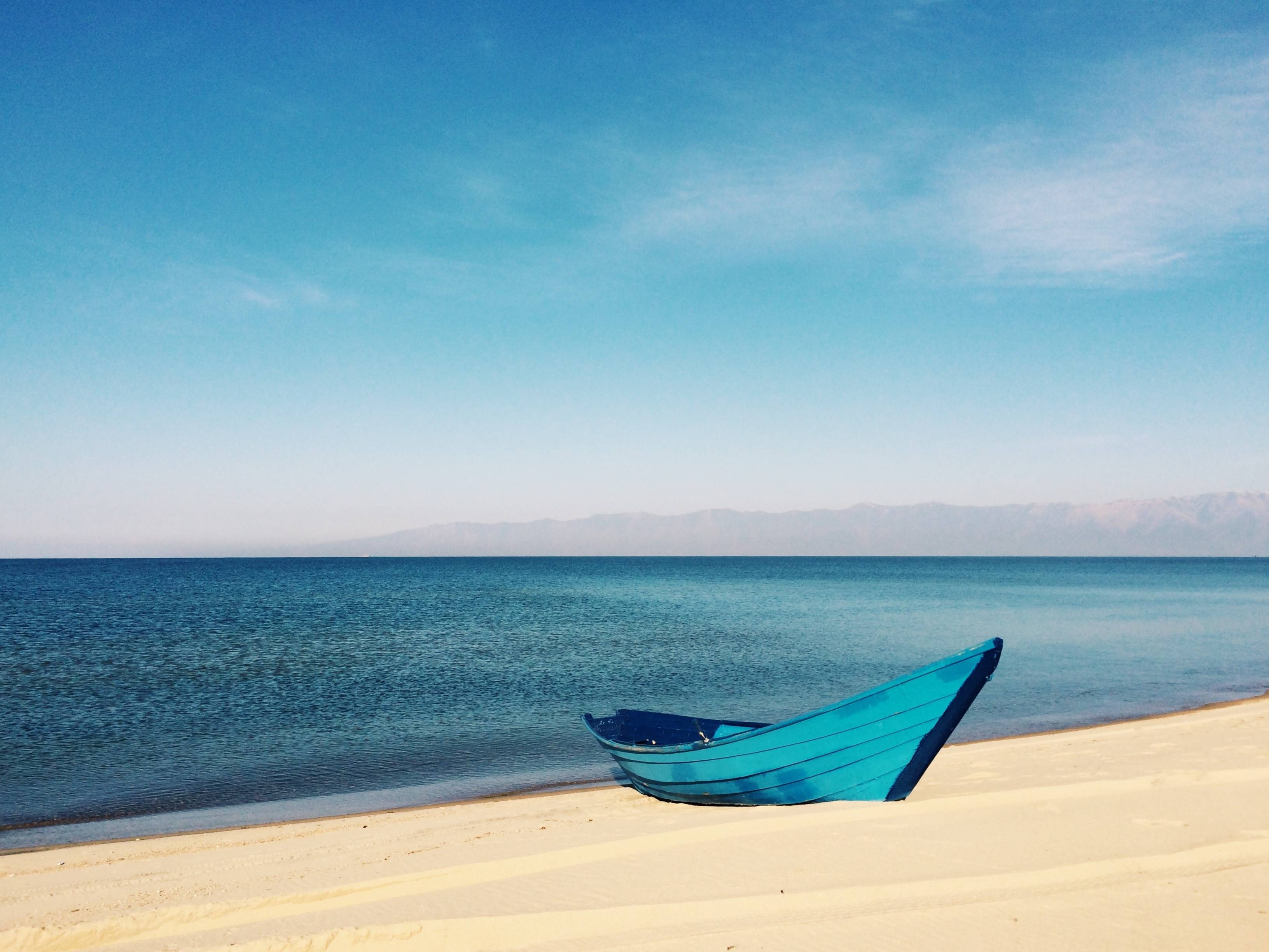 Blue boat on a sandy beach by the ocean HD Wallpaper