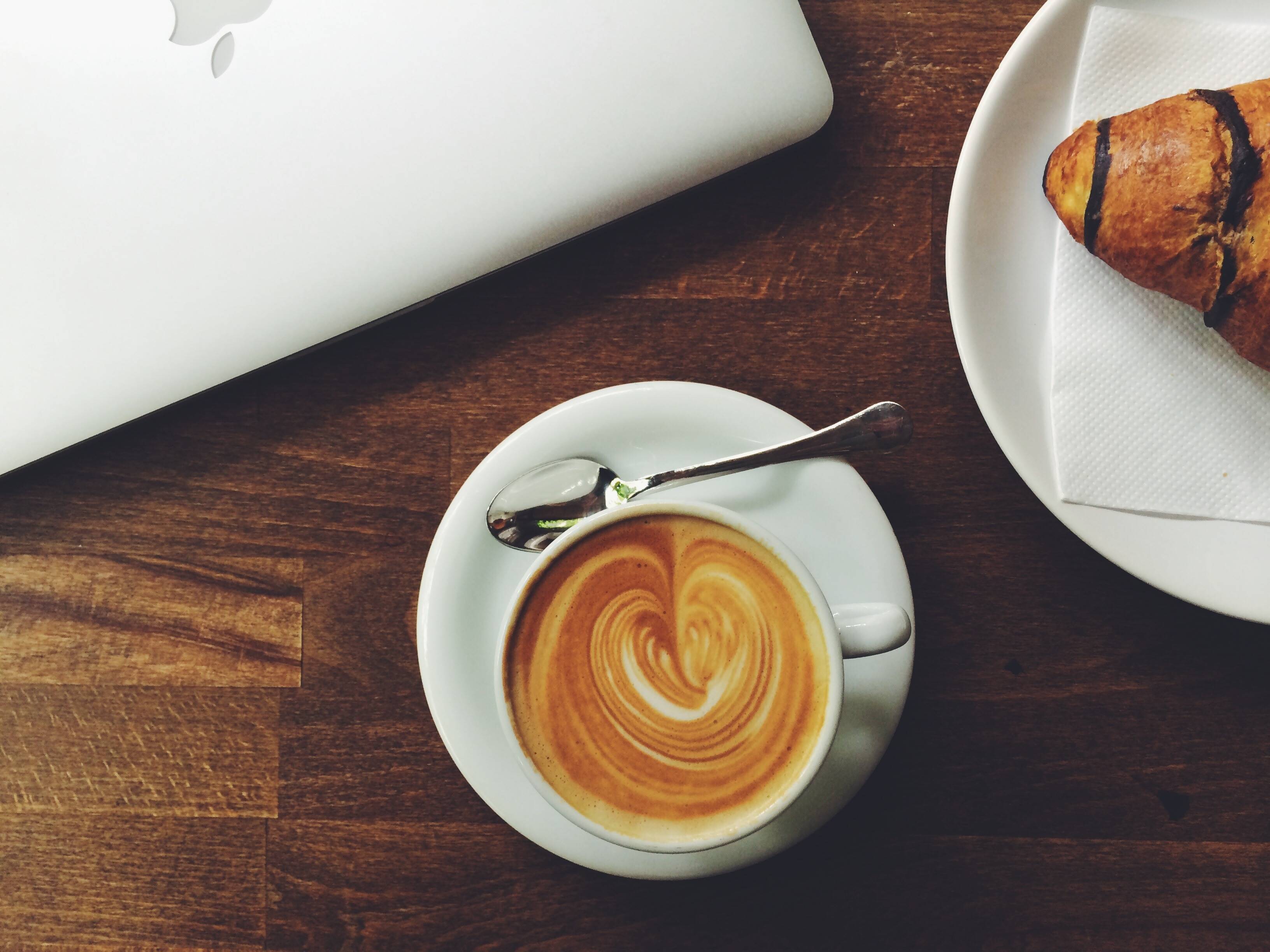 Latte art and croissant next to Apple laptop HD Wallpaper