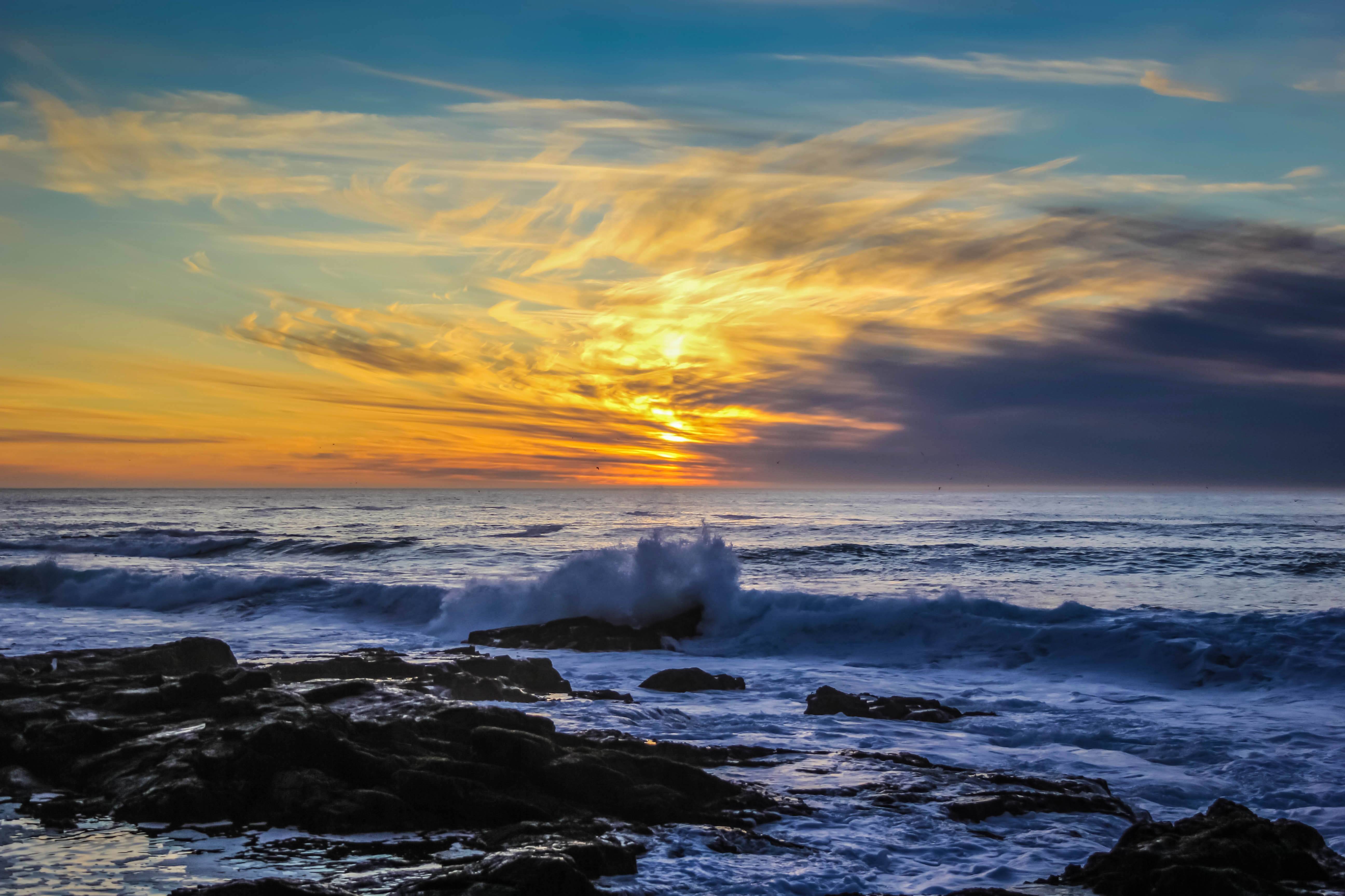 Ocean waves crashing on rocks at sunset HD Wallpaper