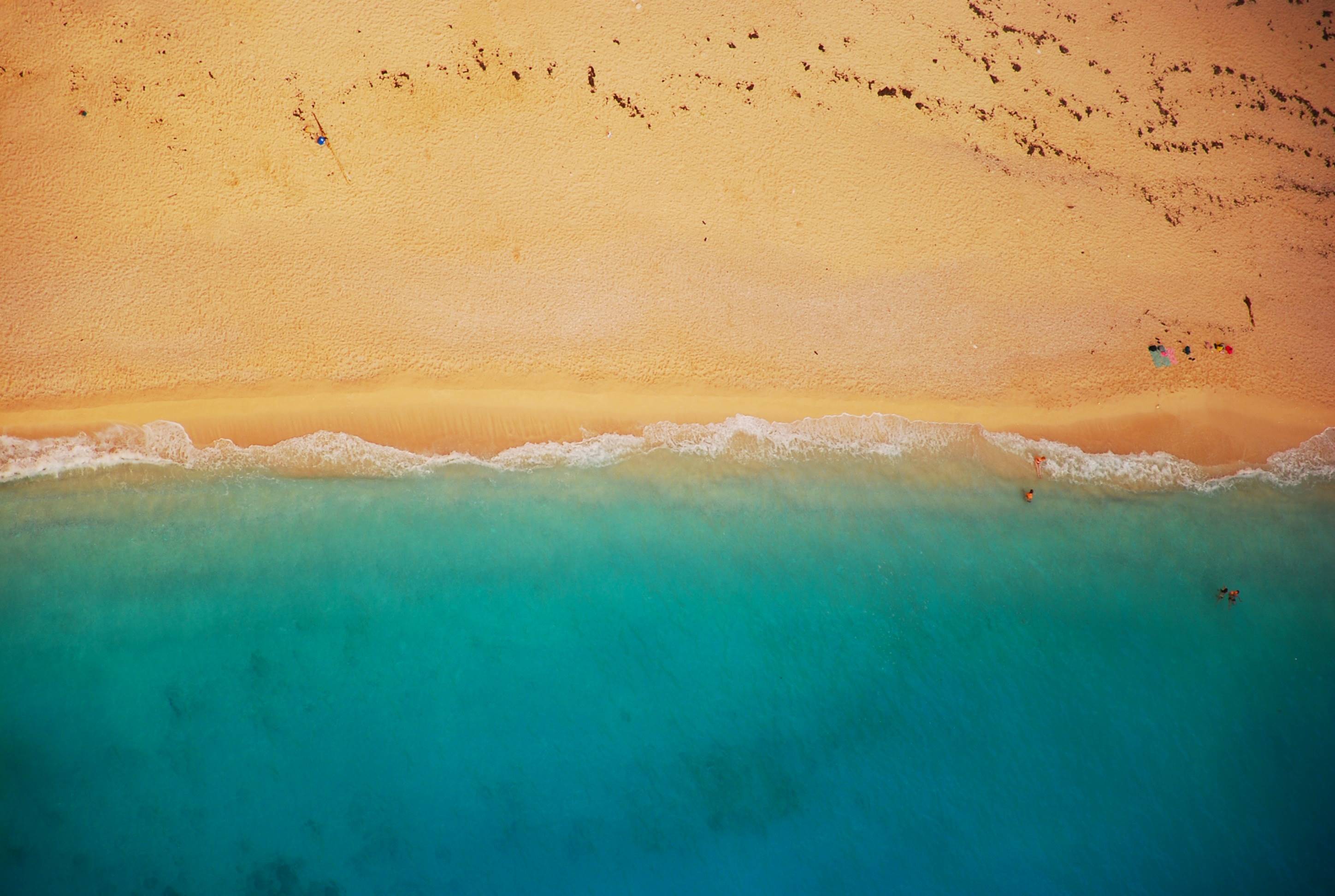 Aerial view of a sandy beach and turquoise ocean waves HD Wallpaper
