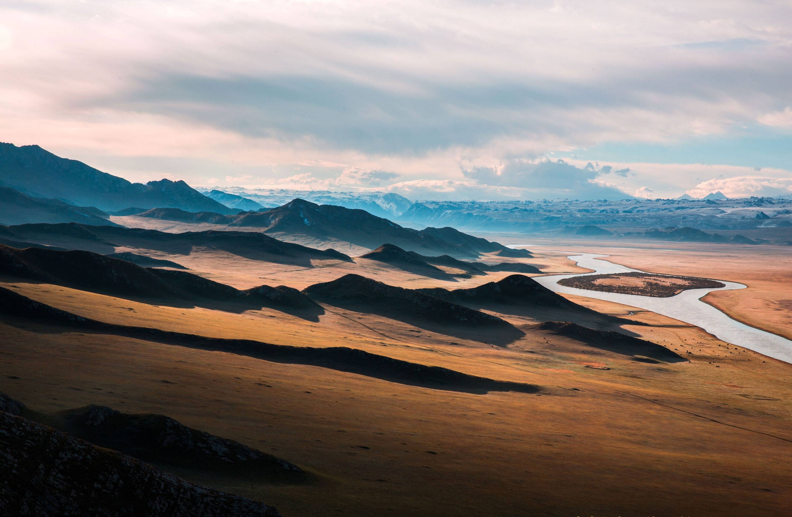River flowing through a vast mountain landscape with rolling hills HD Wallpaper