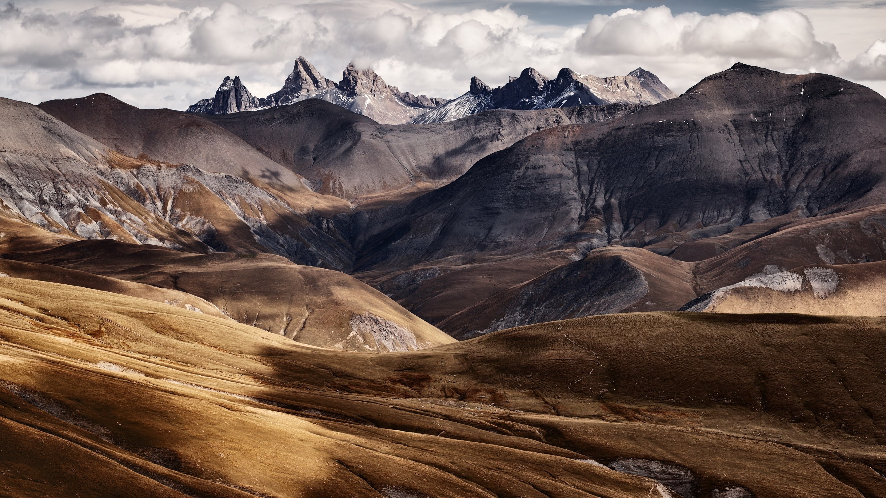 Jagged mountain peaks under a cloudy sky HD Wallpaper