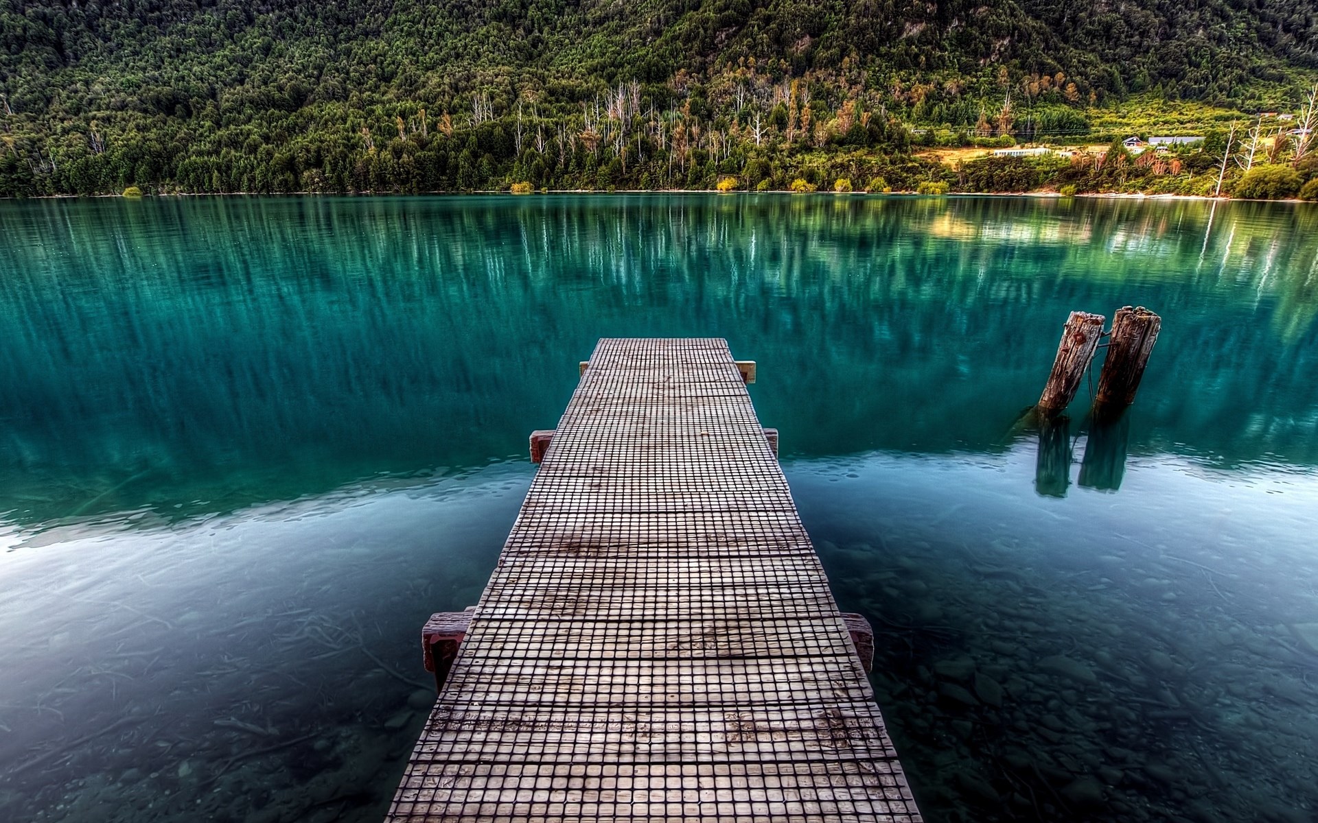 Wooden pier on a turquoise lake with forested mountains HD Wallpaper