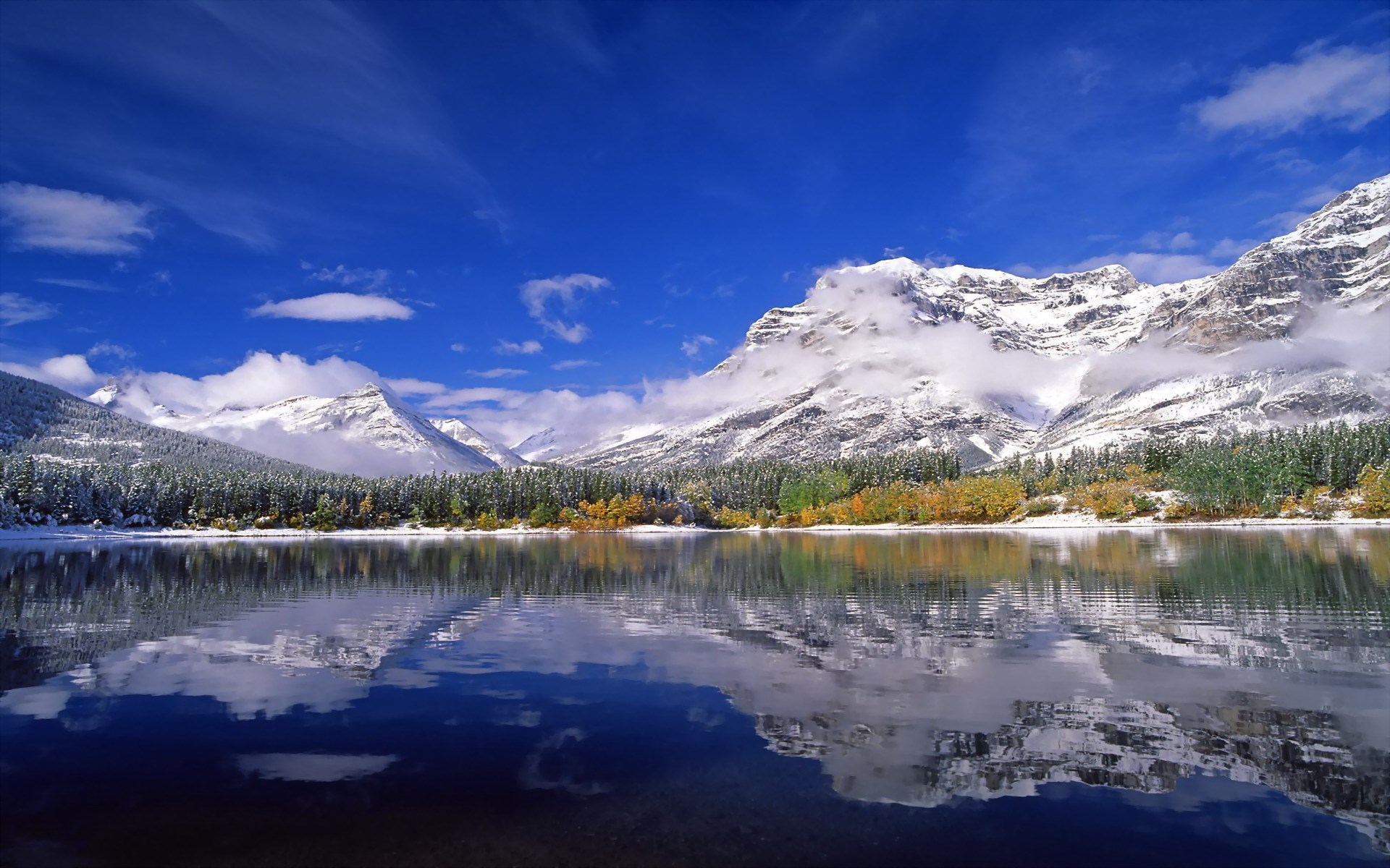 Snow-capped mountains reflected in a calm lake HD Wallpaper