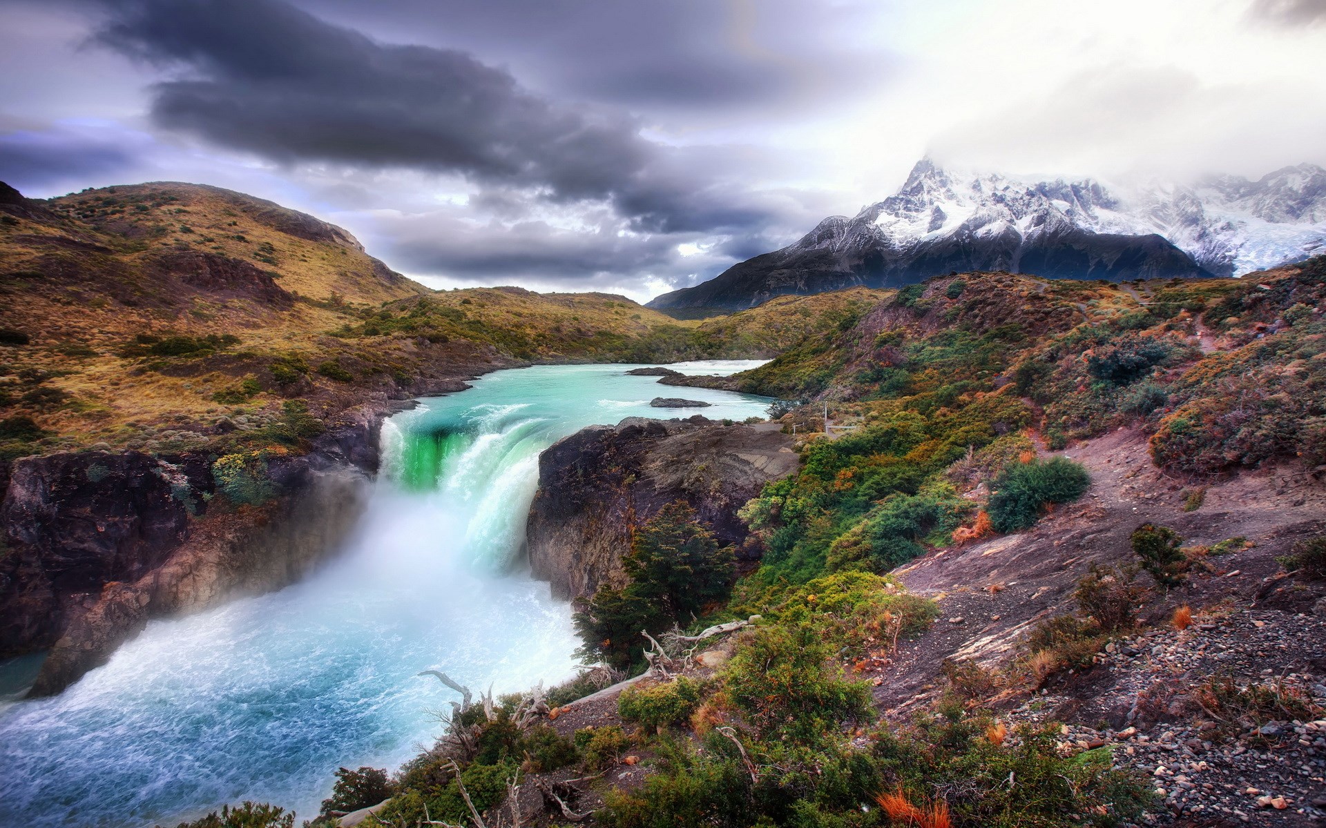 Waterfall flowing into a turquoise lake with mountains HD Wallpaper