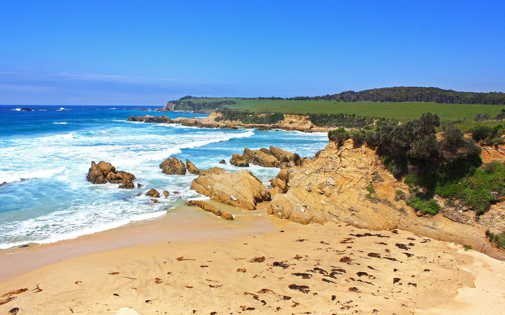Rocky coastline with sandy beach and ocean waves HD Wallpaper