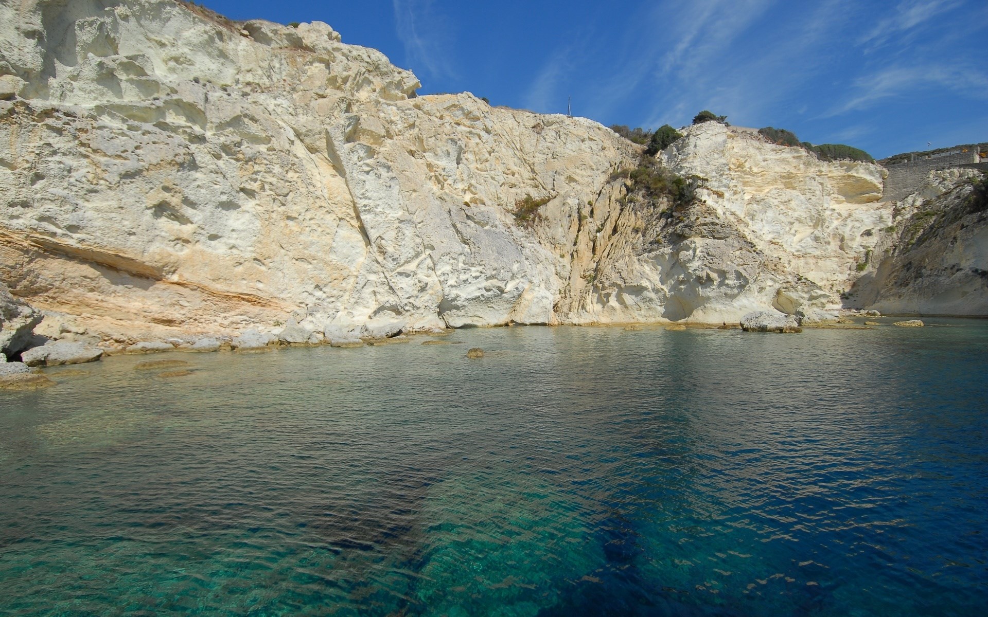 White cliffs meet turquoise water under a blue sky HD Wallpaper