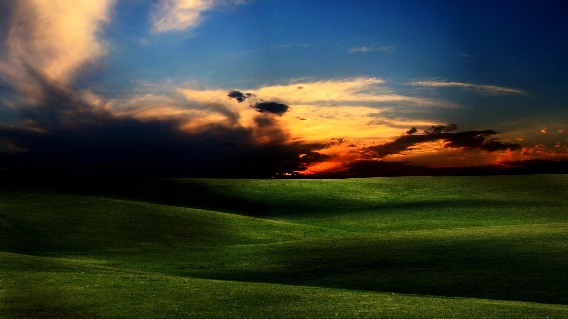 Rolling green hills under a dramatic sunset sky HD Wallpaper
