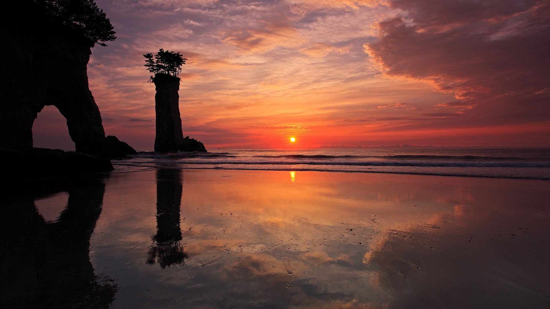 Sunset over a beach with rock formations HD Wallpaper