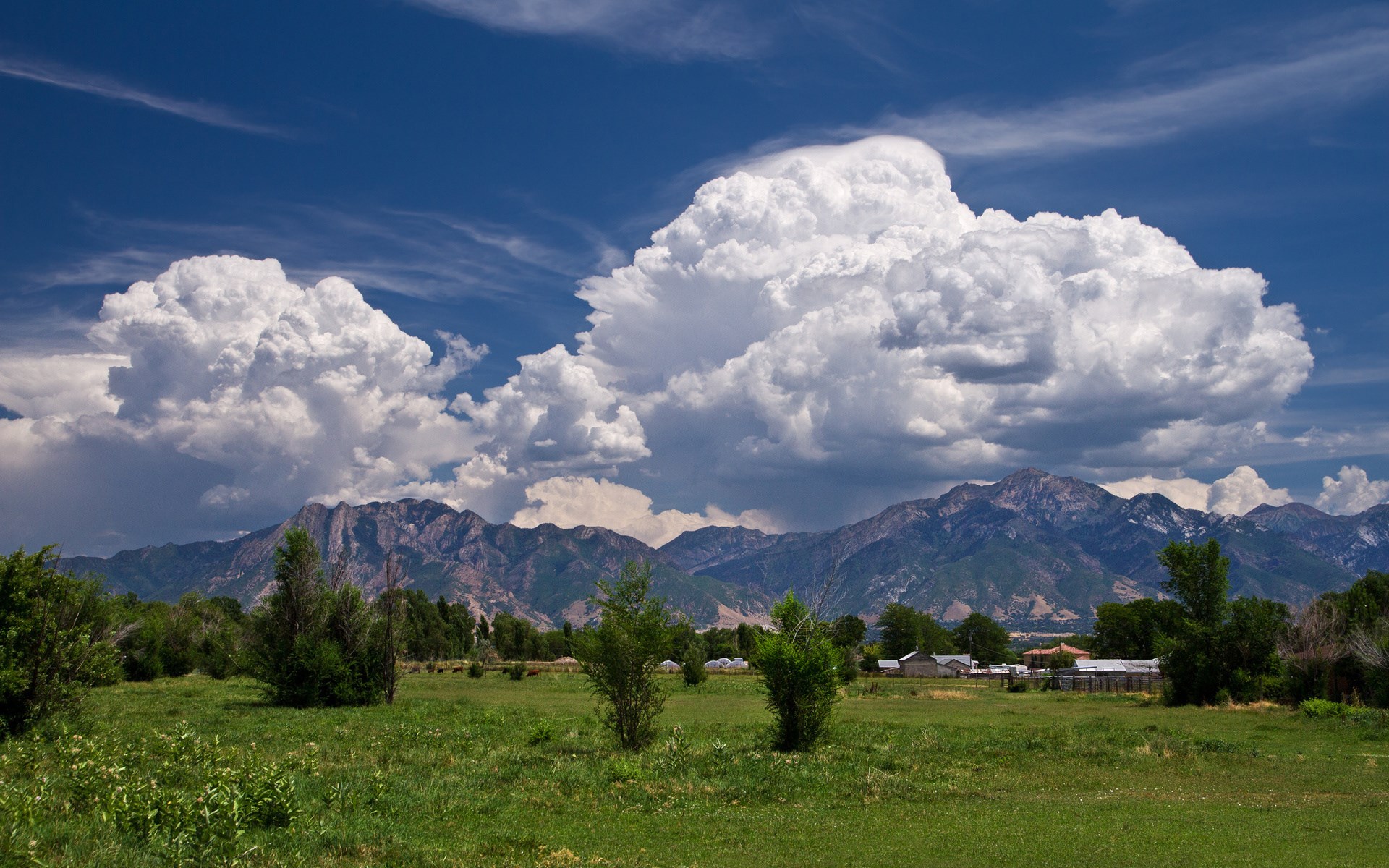 Cumulus clouds over mountains and a field HD Wallpaper
