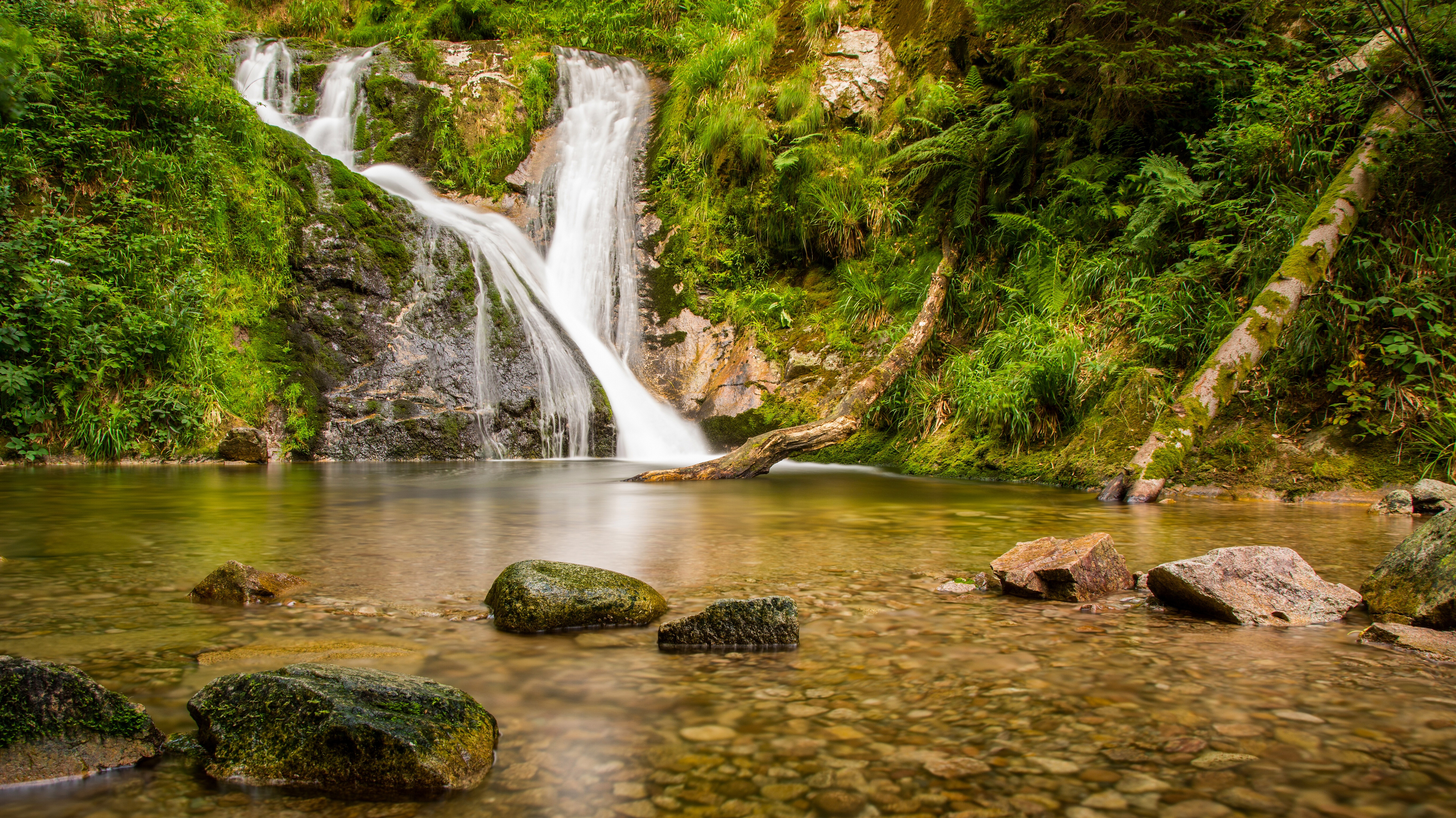 Waterfall cascading into a clear pool with rocks HD Wallpaper