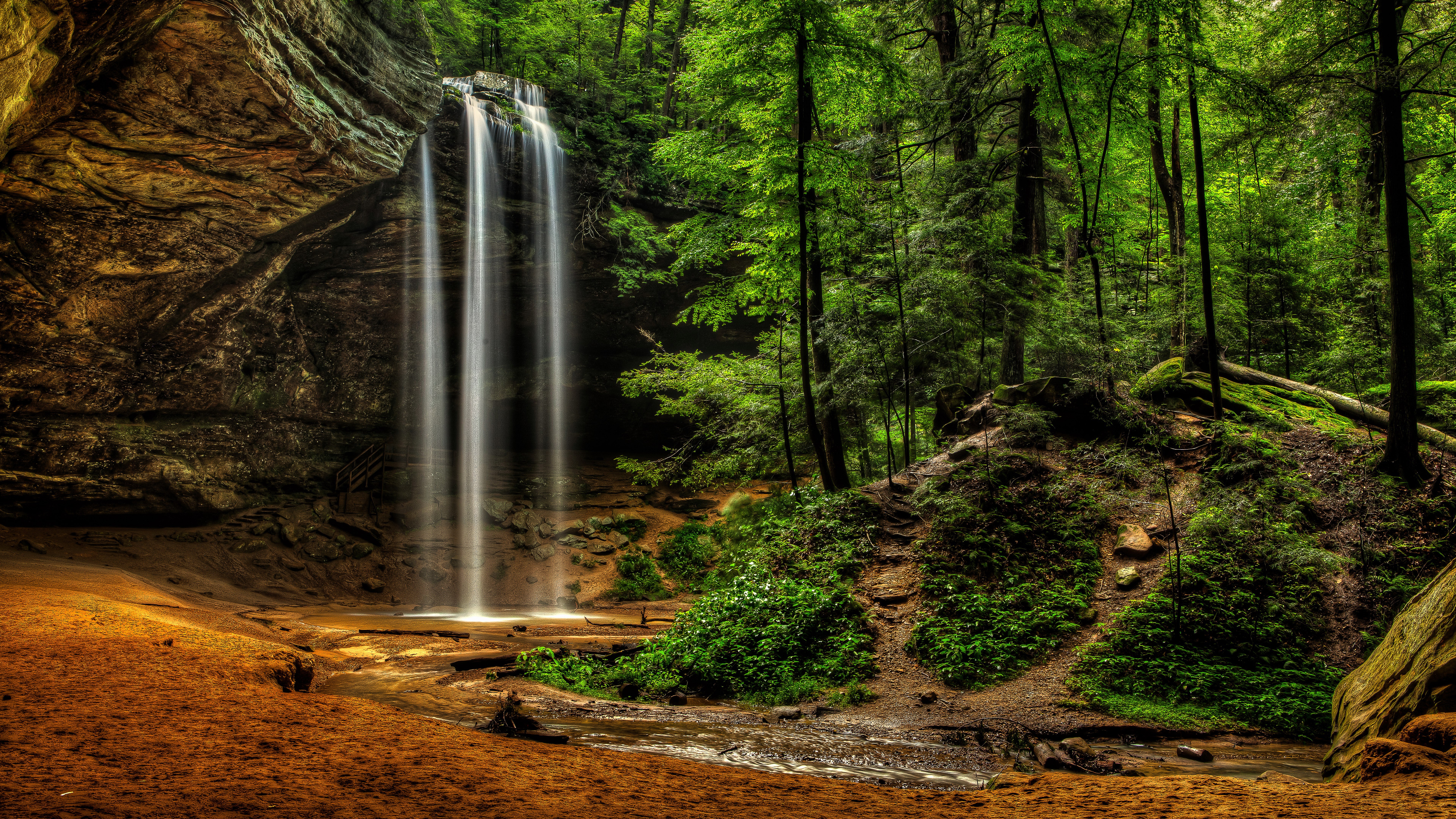 Waterfall in a lush green forest cave HD Wallpaper