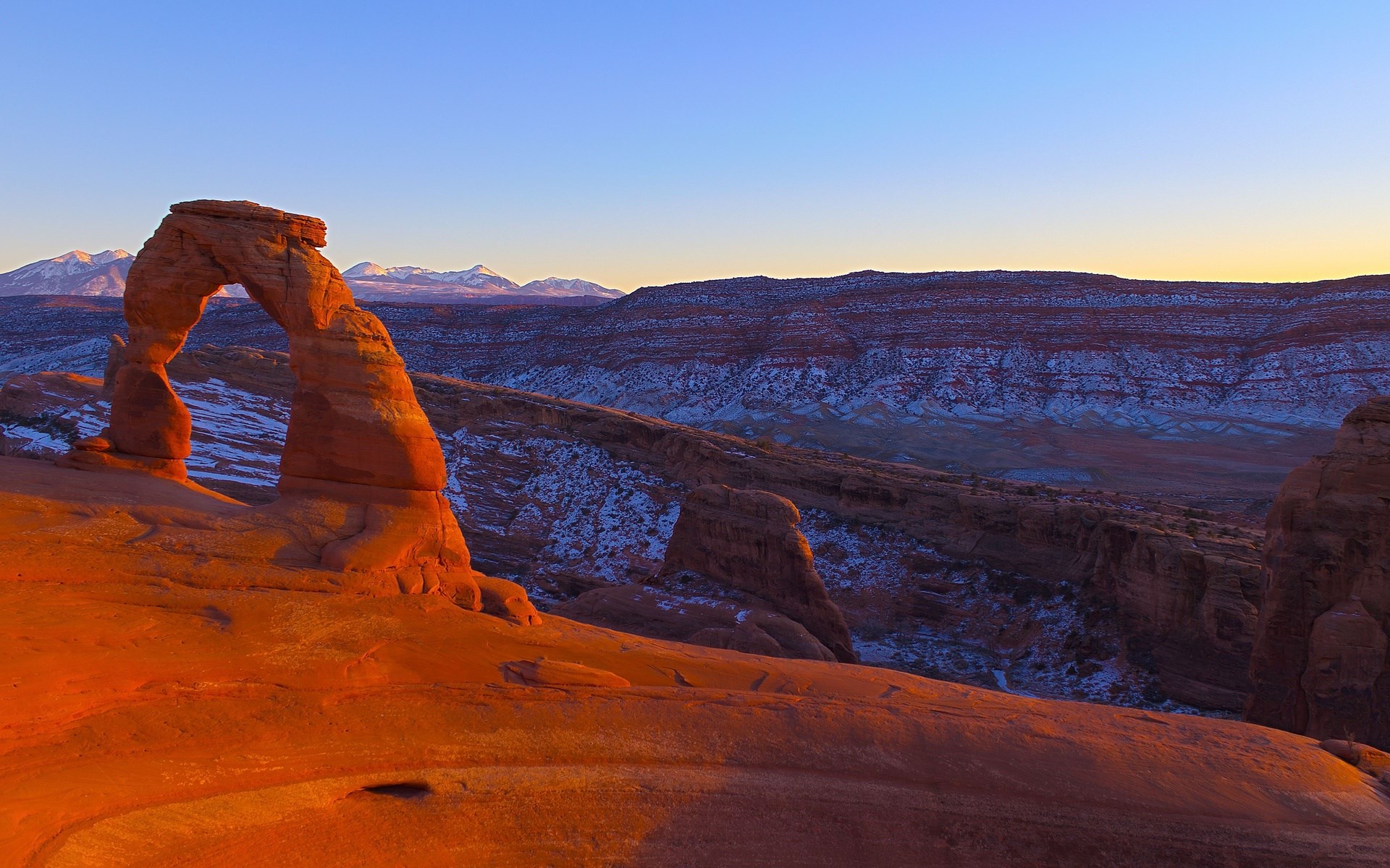 Delicate Arch at sunrise with snow-capped mountains HD Wallpaper