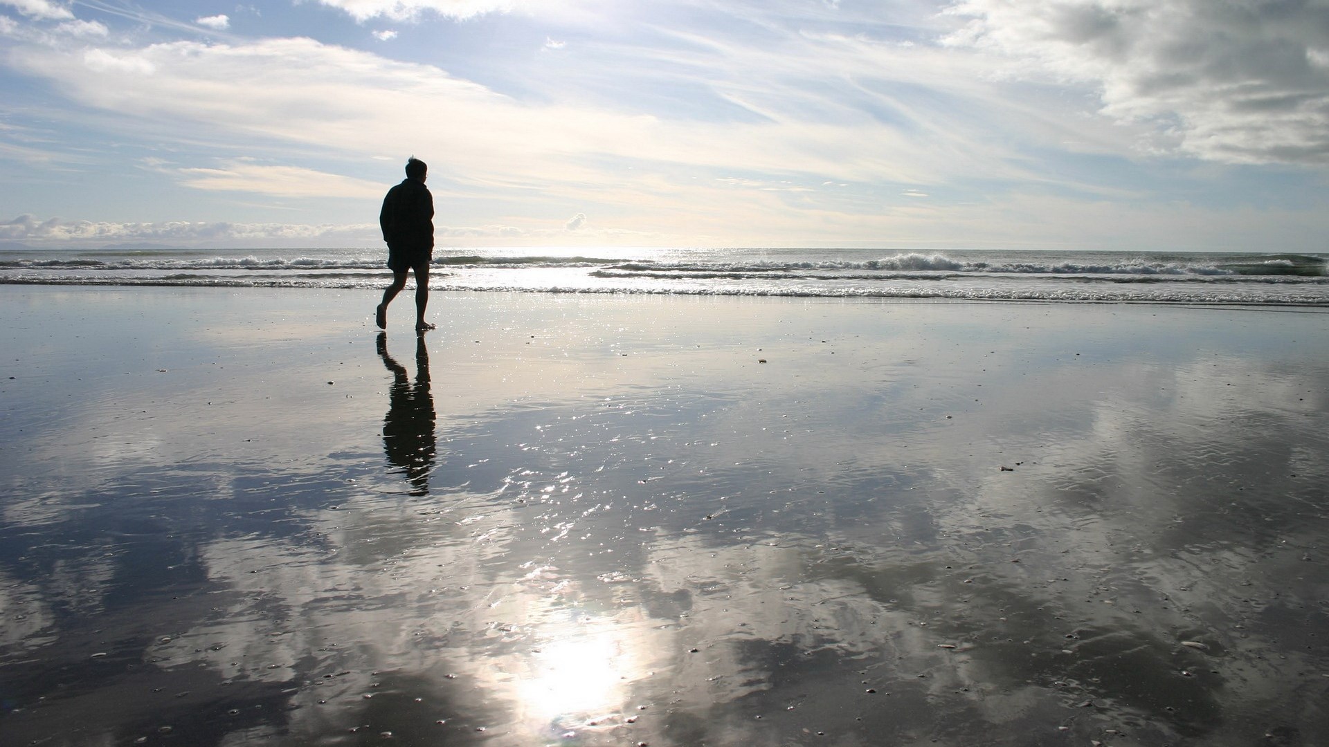 Person walking on a wet beach with reflections HD Wallpaper