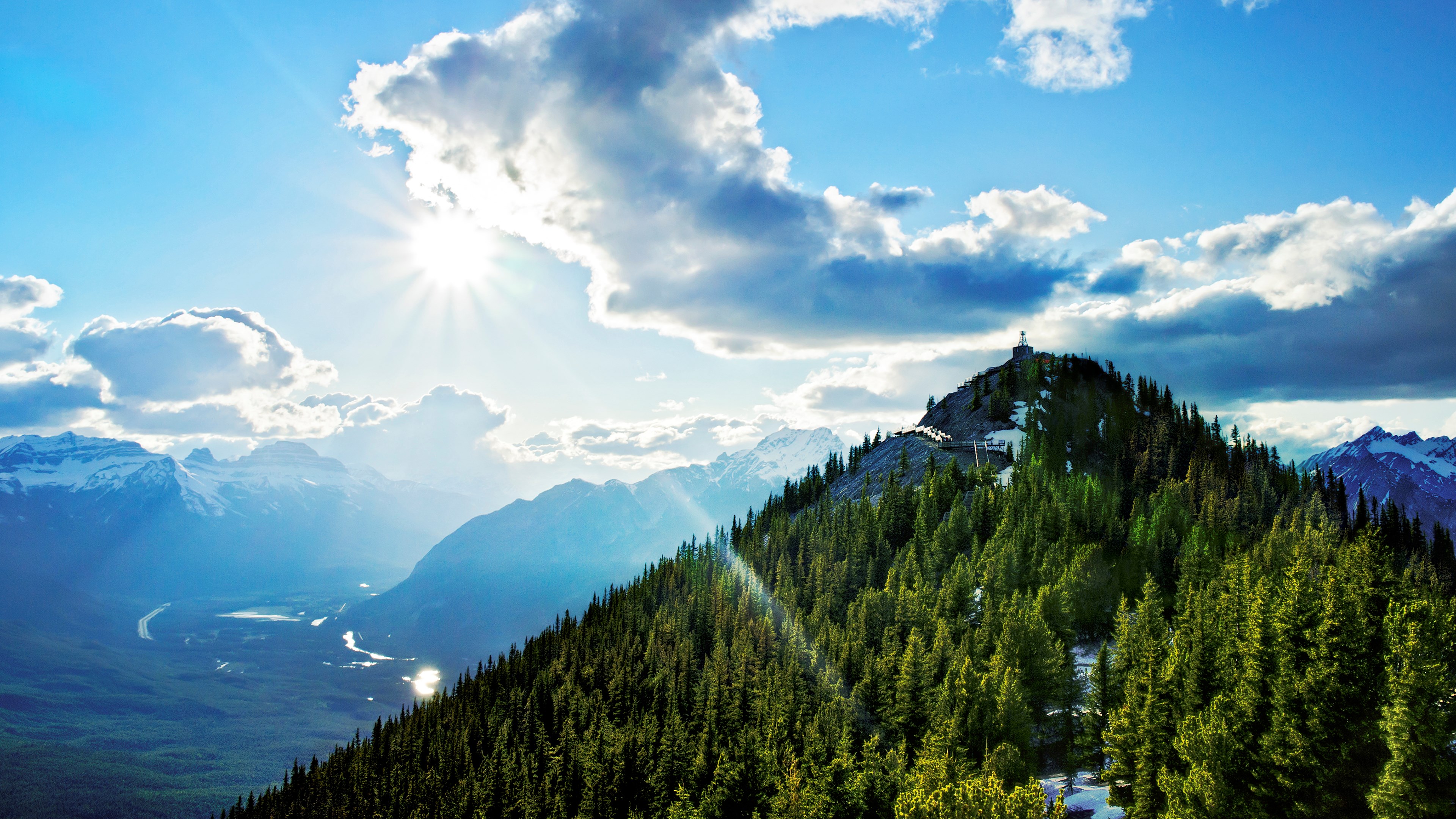 Mountain peak with trees and sunlit clouds HD Wallpaper