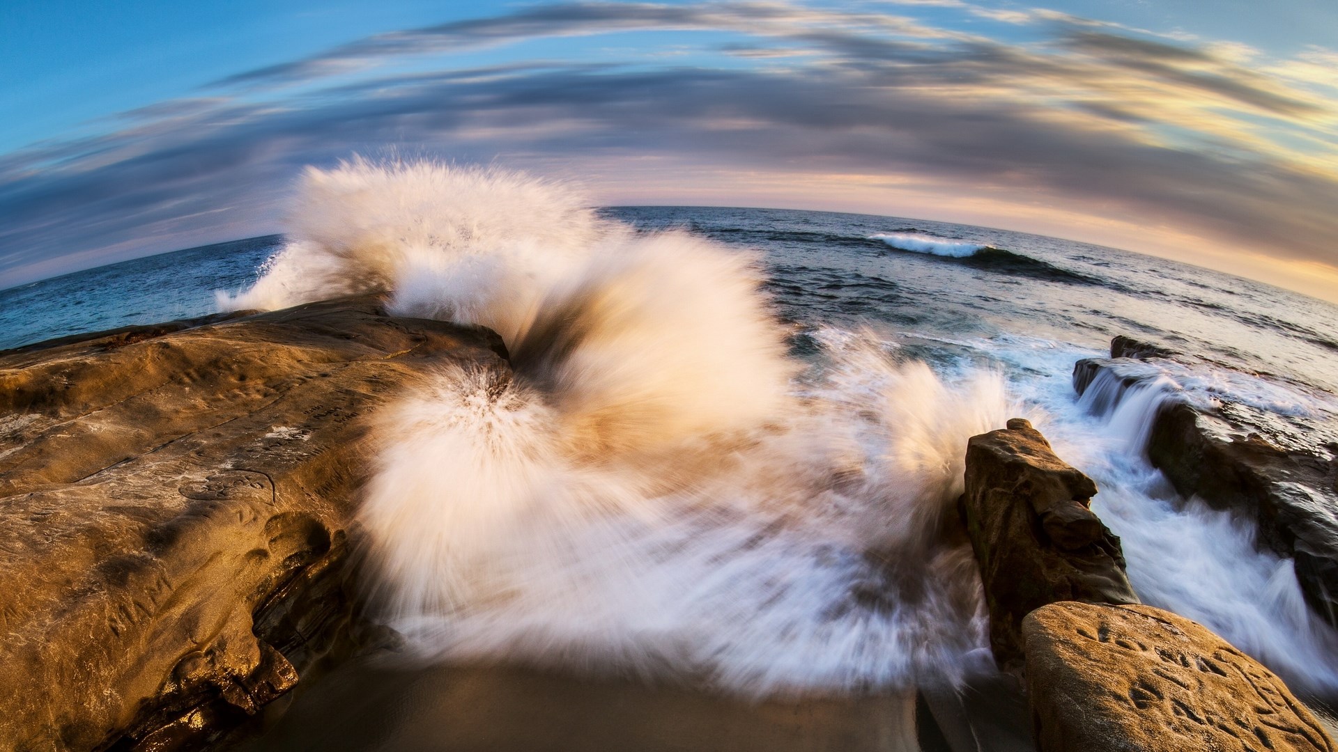 Wave crashing on rocky shore at sunset HD Wallpaper