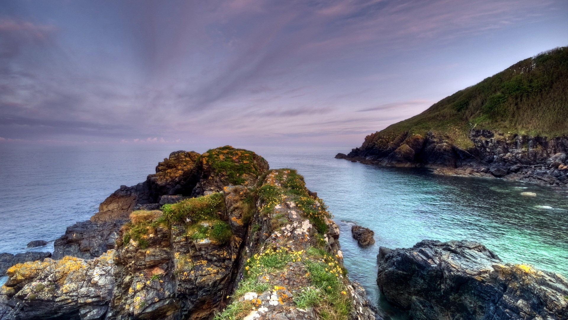 Rocky coastline with calm sea and cloudy sky HD Wallpaper
