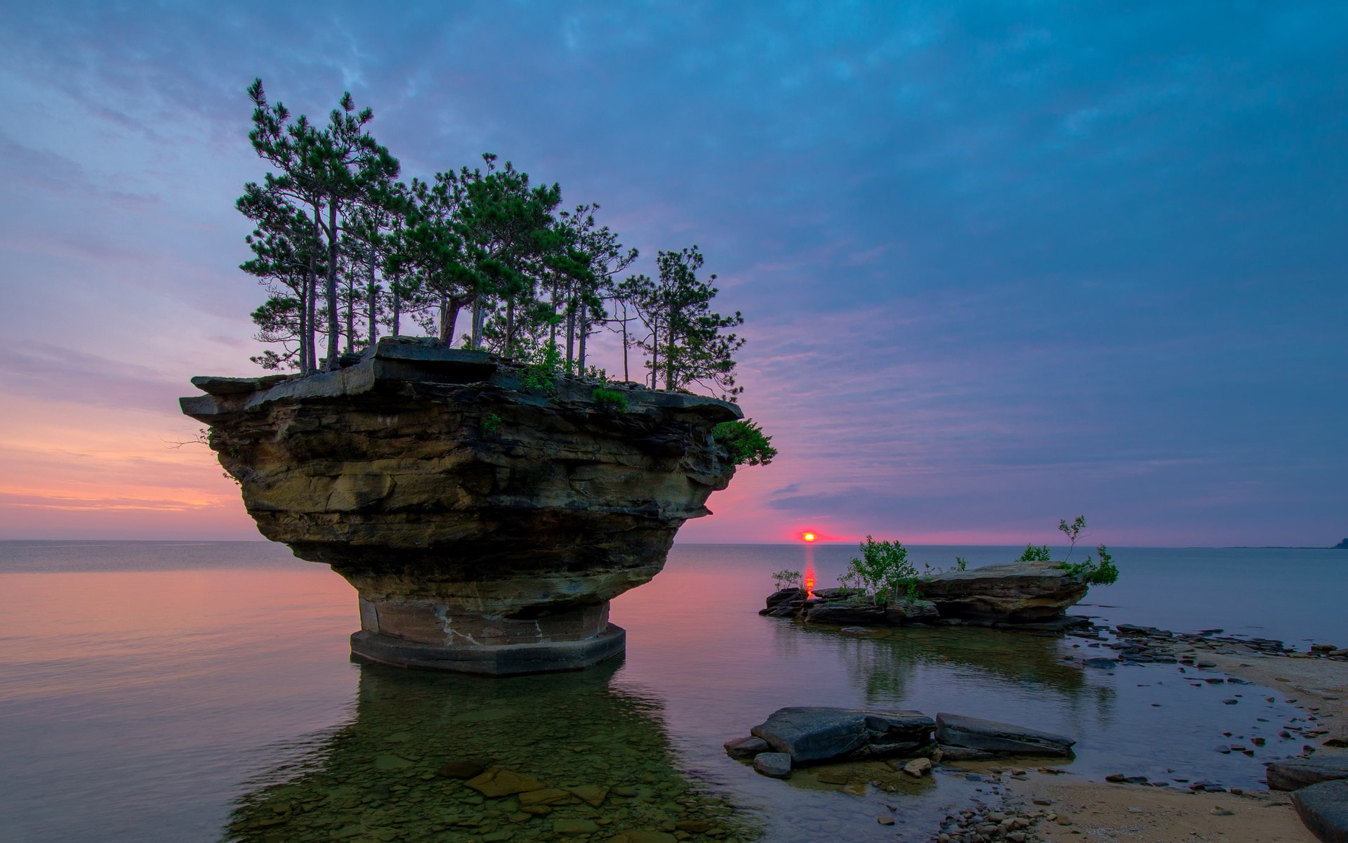 Sunrise over rock formations with trees in water HD Wallpaper