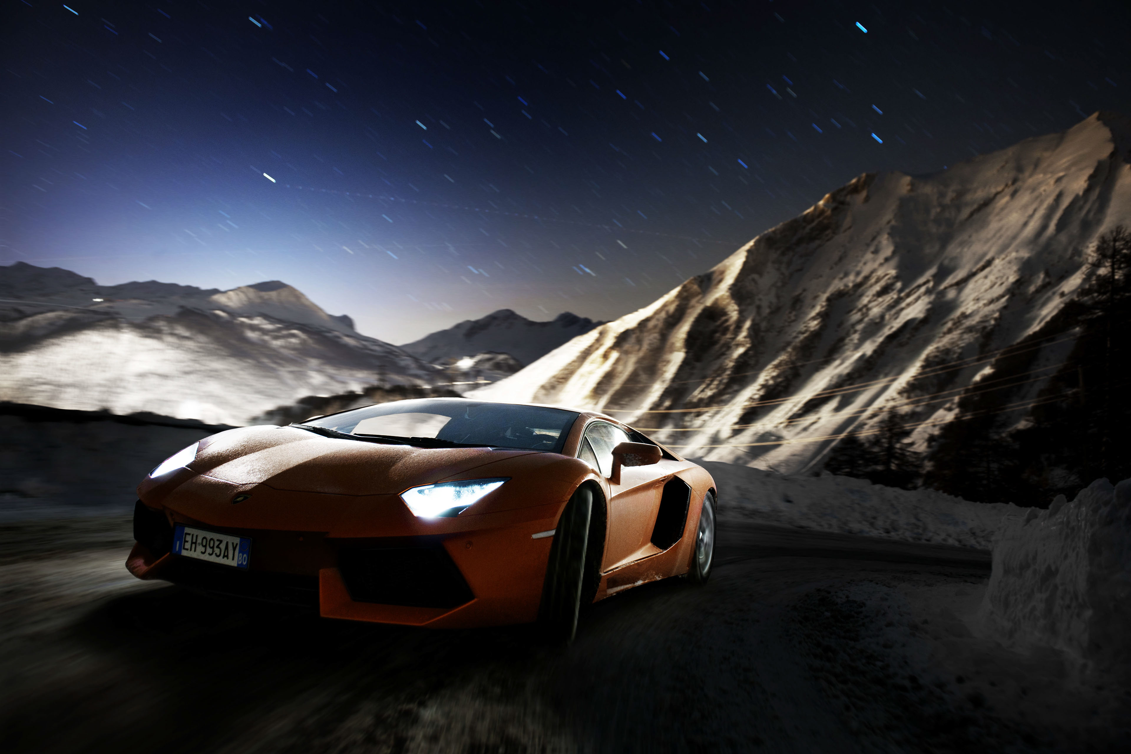 Orange Lamborghini Aventador driving on snowy mountain road at night HD Wallpaper