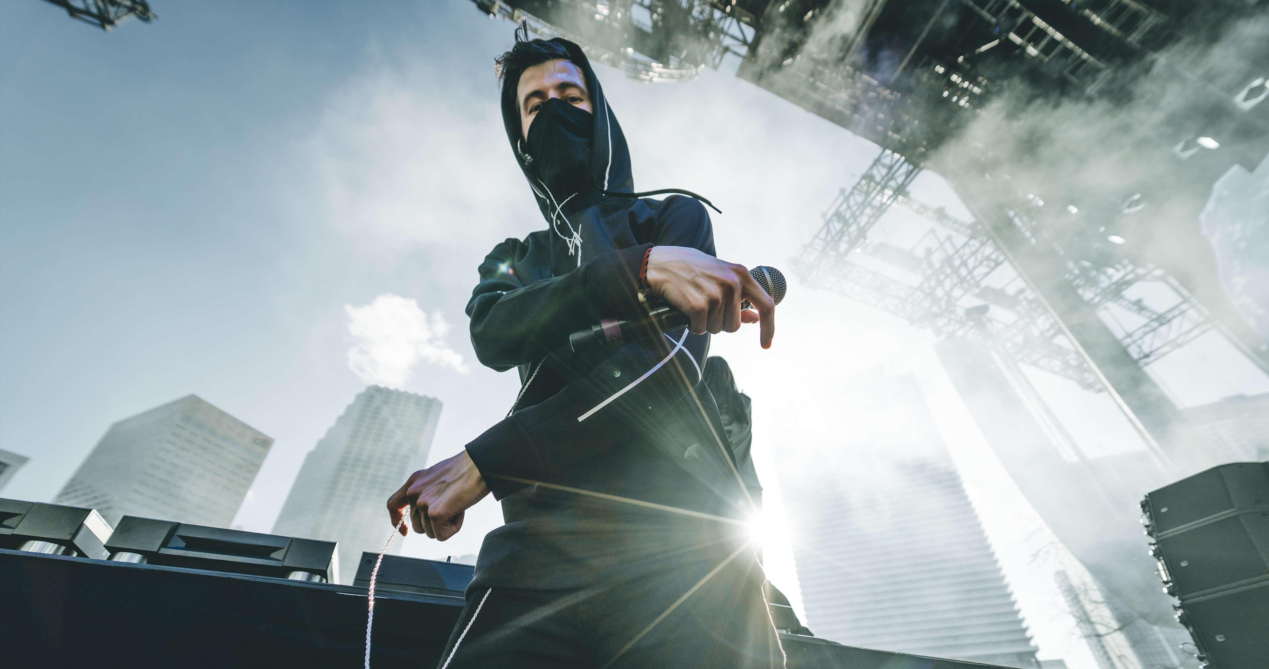 Alan Walker DJ performing on stage with city background HD Wallpaper