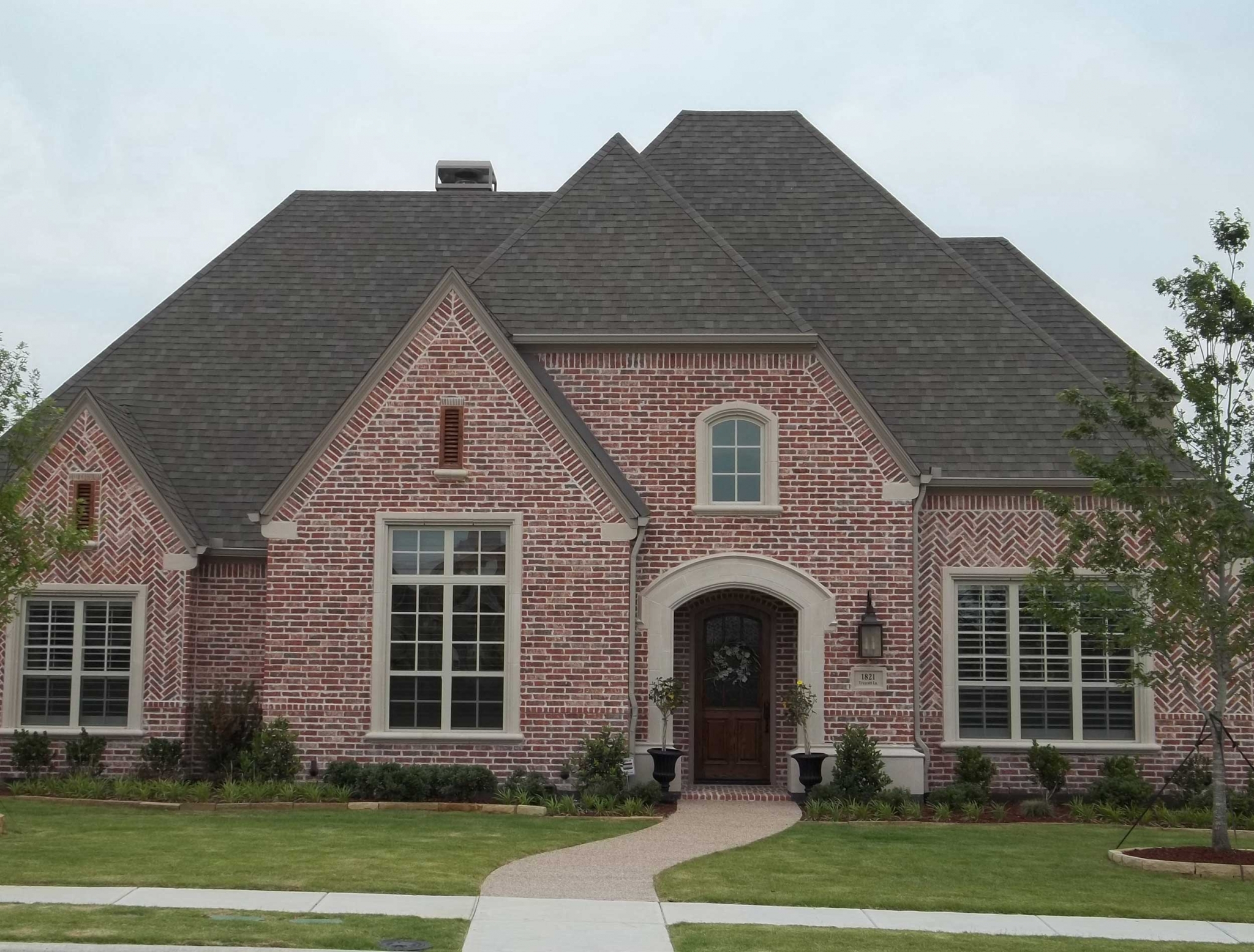 Brick house with arched entryway and large windows HD Wallpaper