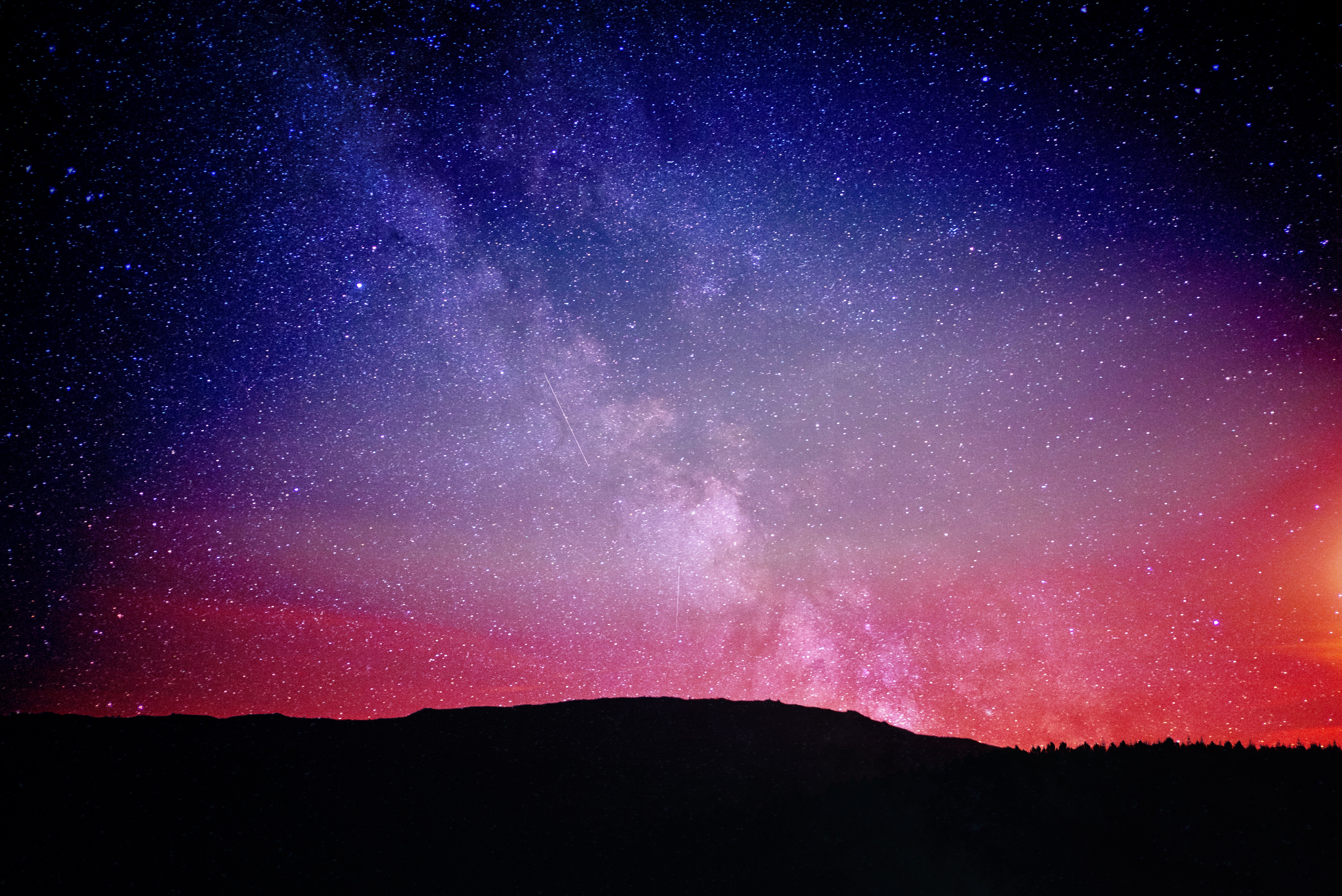 Milky Way galaxy over a silhouetted landscape HD Wallpaper