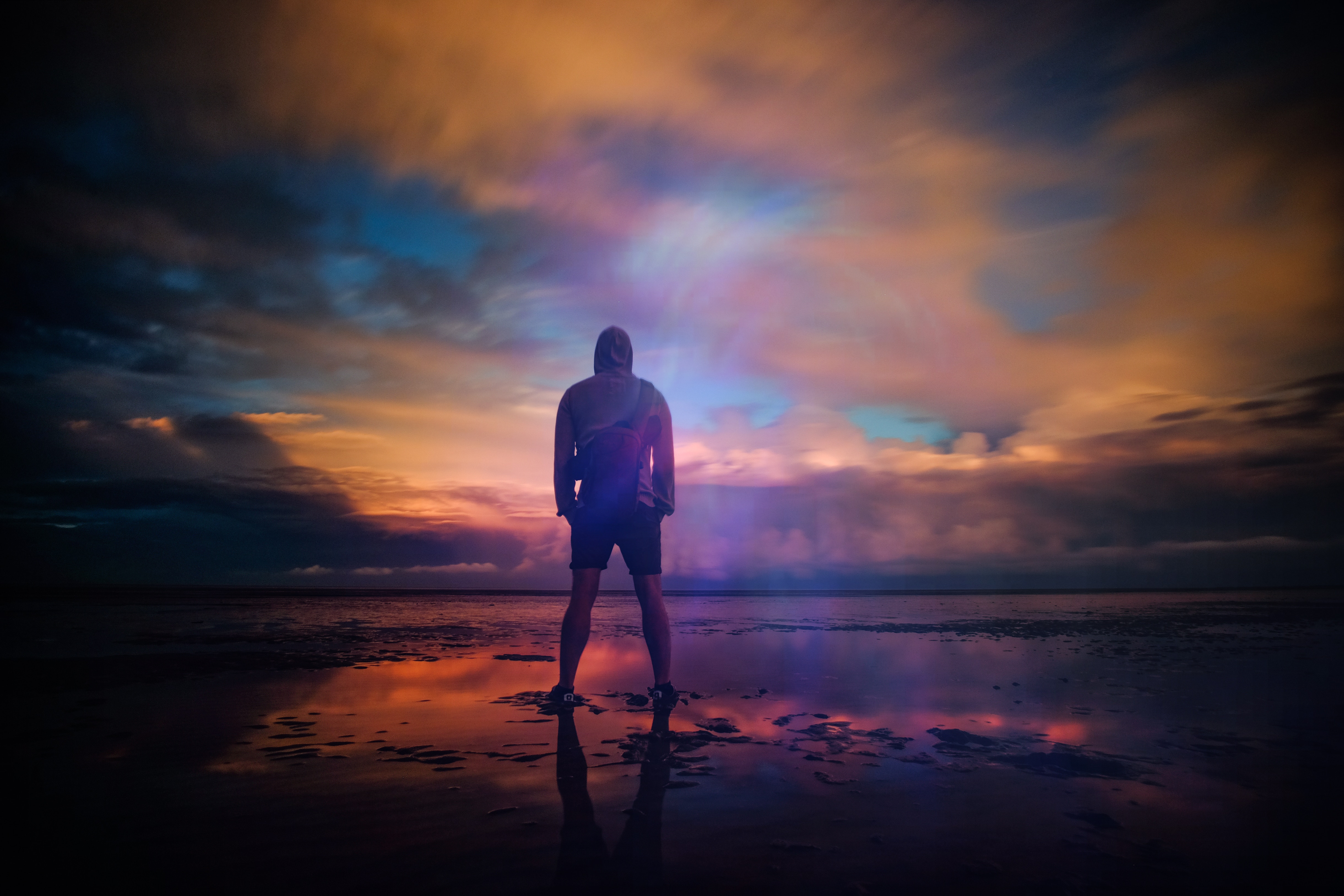 Man standing on a beach at sunset HD Wallpaper