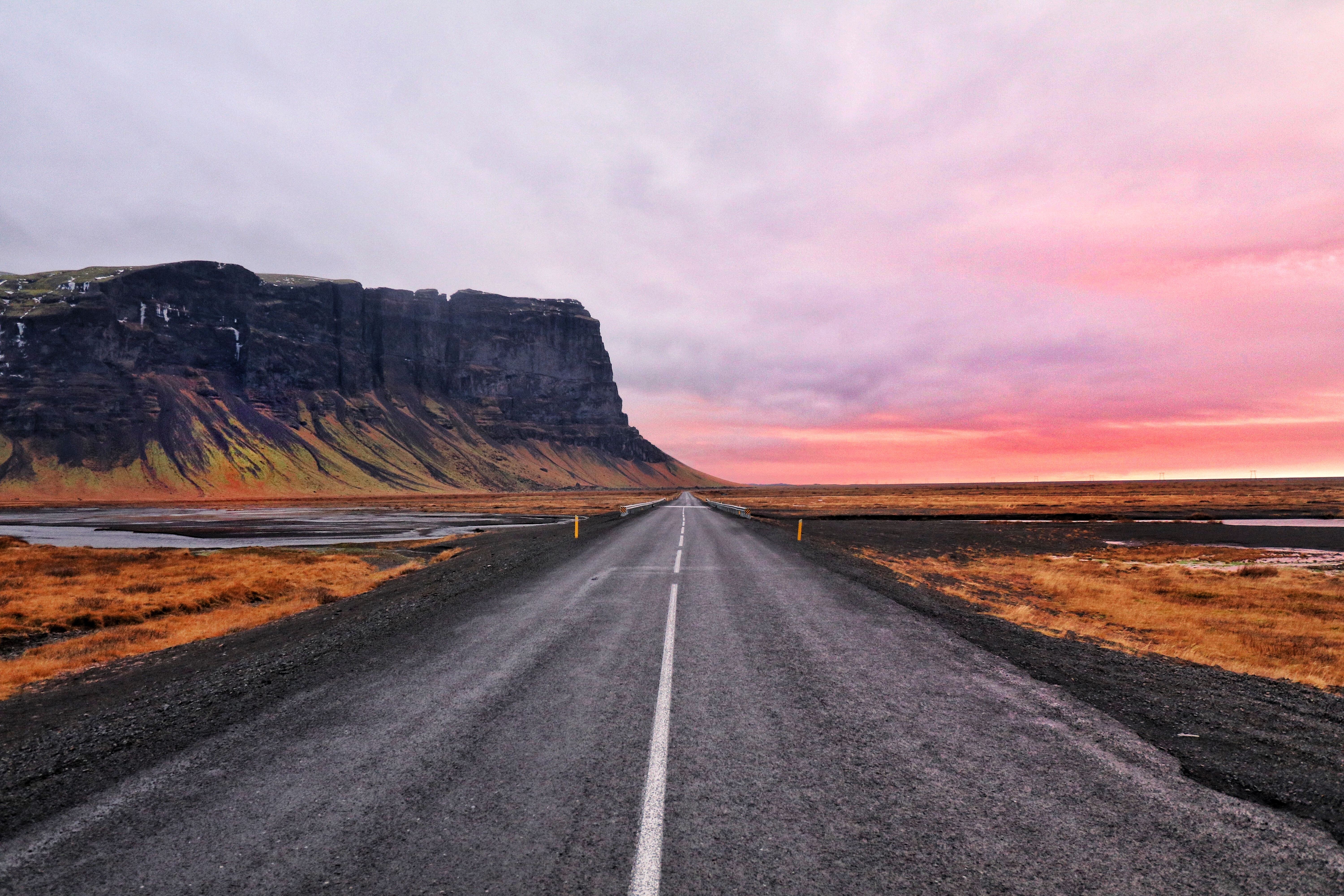 Road leading to a mountain under a pink sky HD Wallpaper