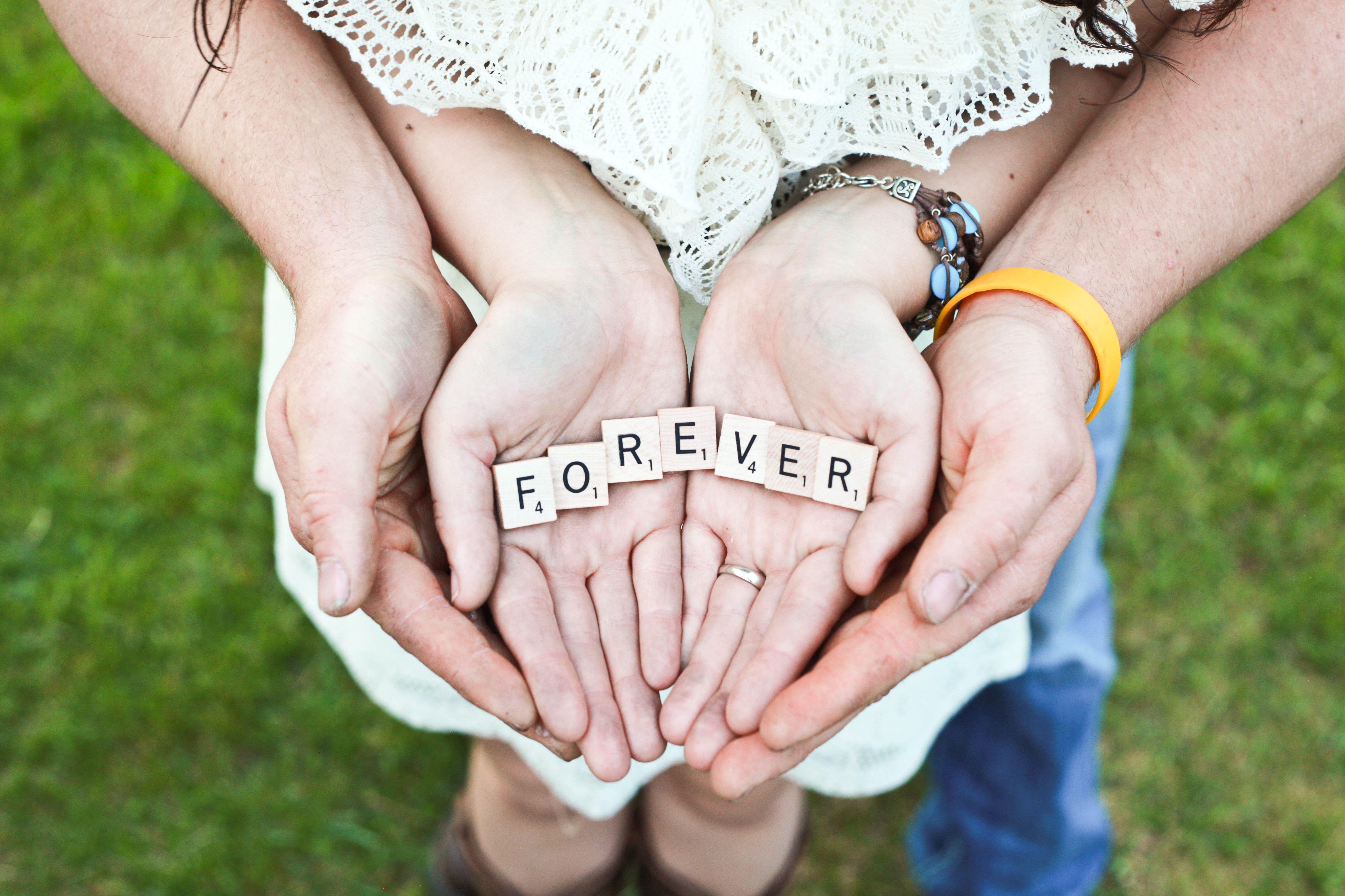 Couple holding scrabble tiles spelling "FOREVER" HD Wallpaper