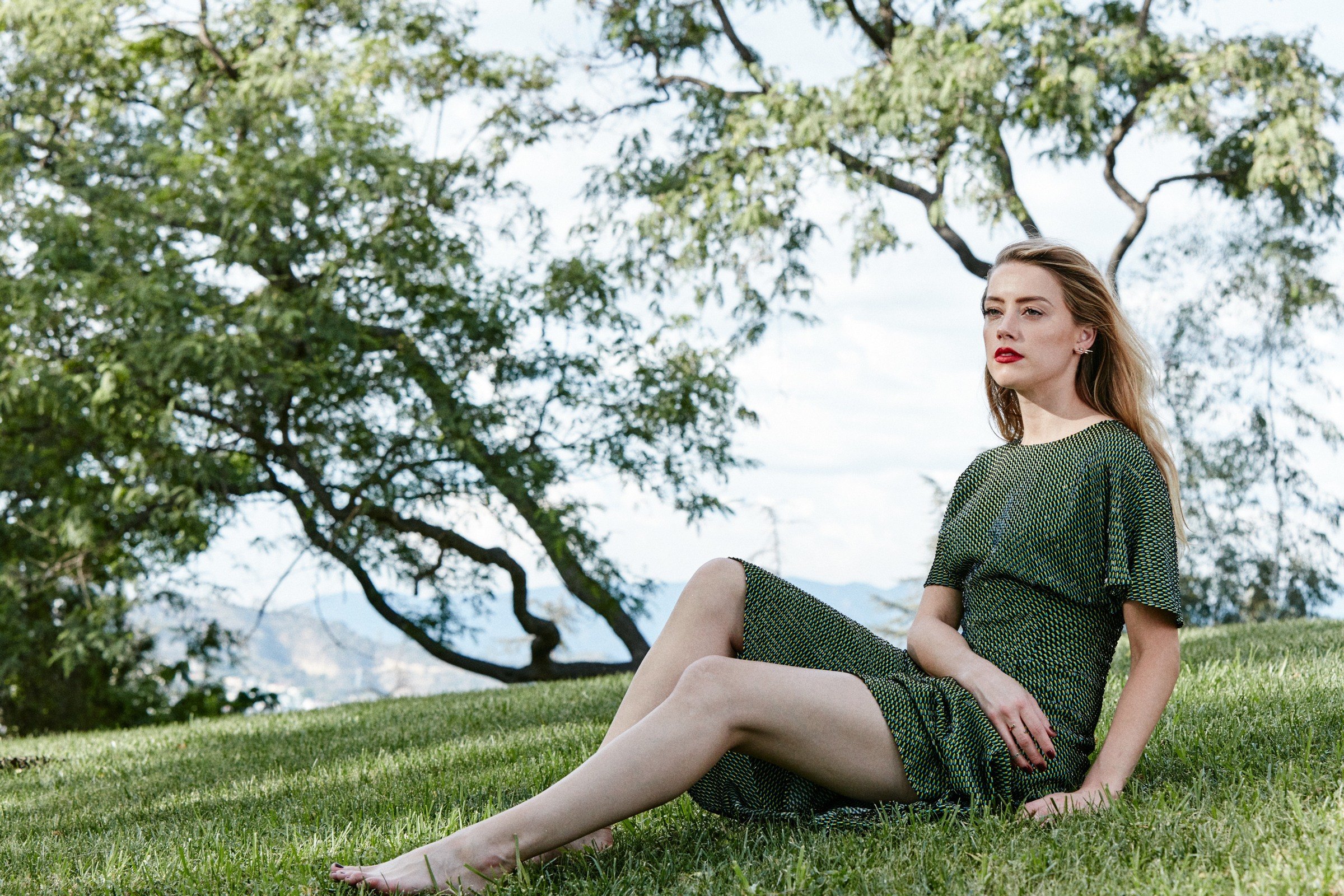 Amber Heard sitting on grass under a tree HD Wallpaper