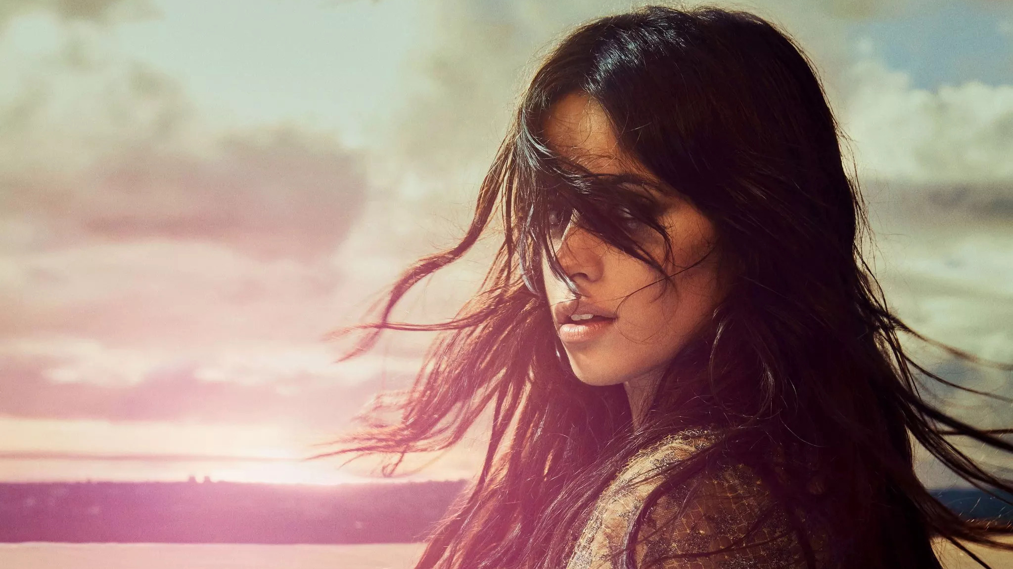 Camila Cabello with windblown hair against a sunset sky HD Wallpaper